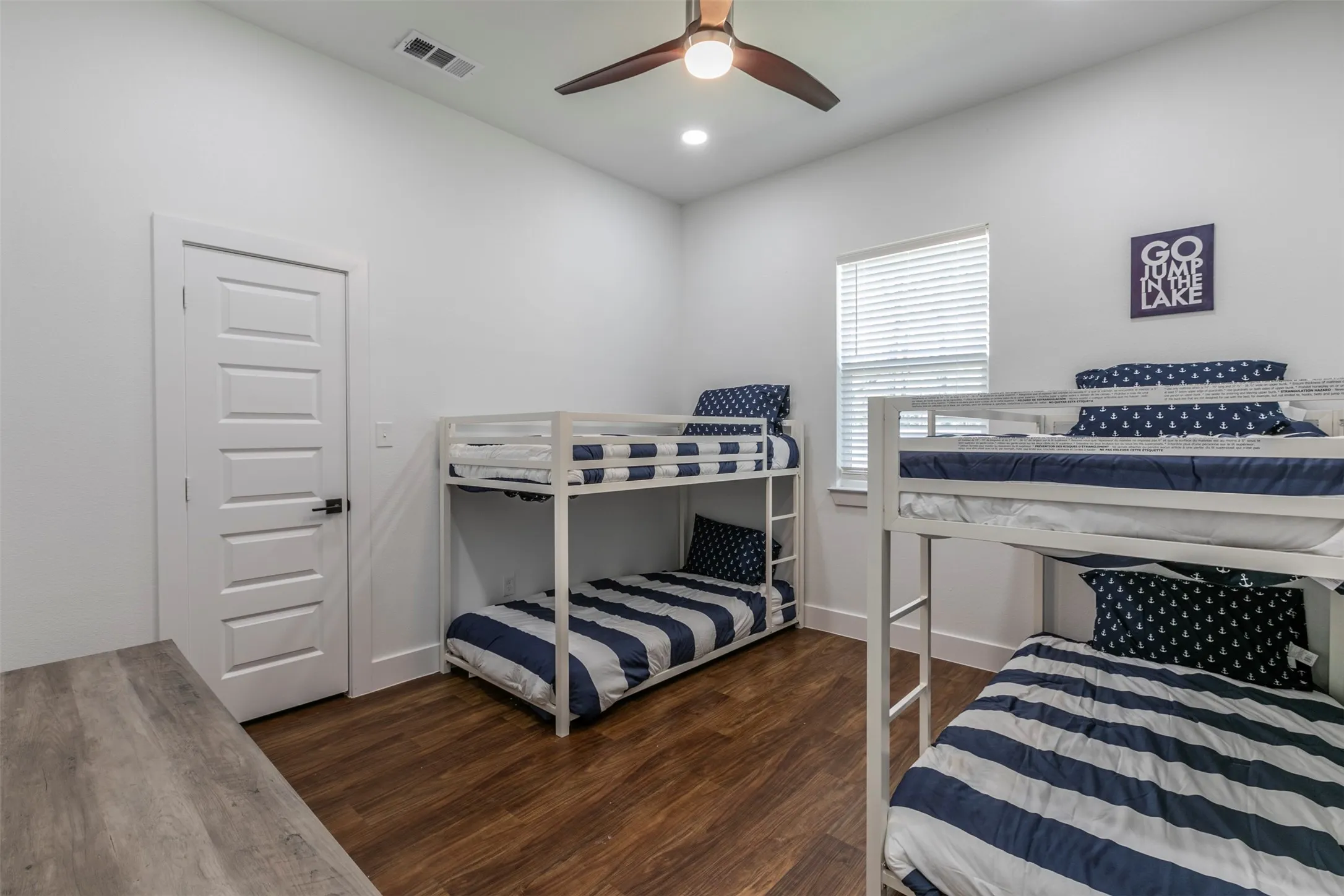 Spacious room featuring wood-finish flooring, a contemporary ceiling fan with integrated lighting, and recessed ceiling lights