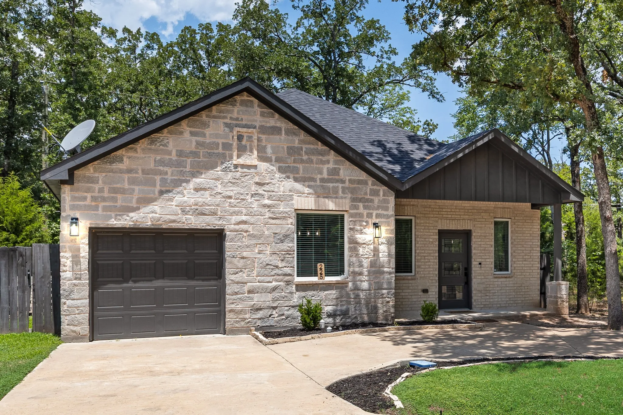 Stone and brick facade residence featuring a dark asphalt shingle roof