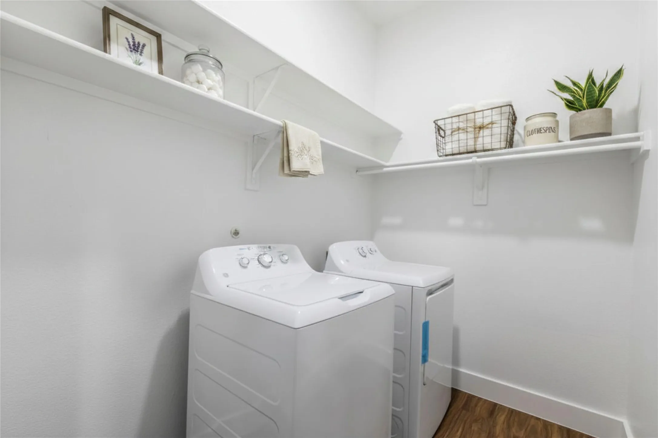 Dedicated laundry area featuring wood-finish flooring, white walls, and built-in shelving