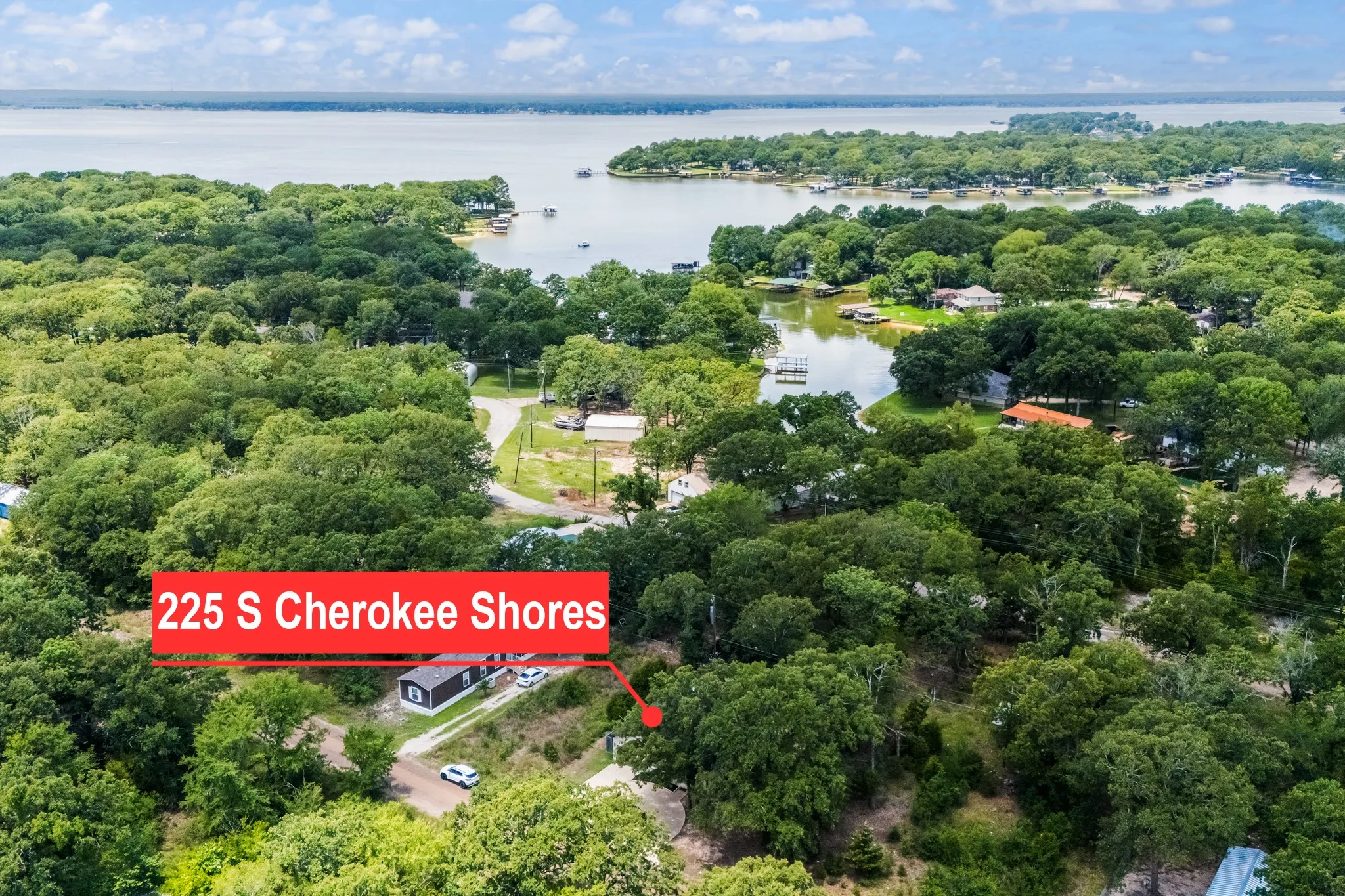 Aerial perspective highlighting a property with abundant mature trees and partial water frontage