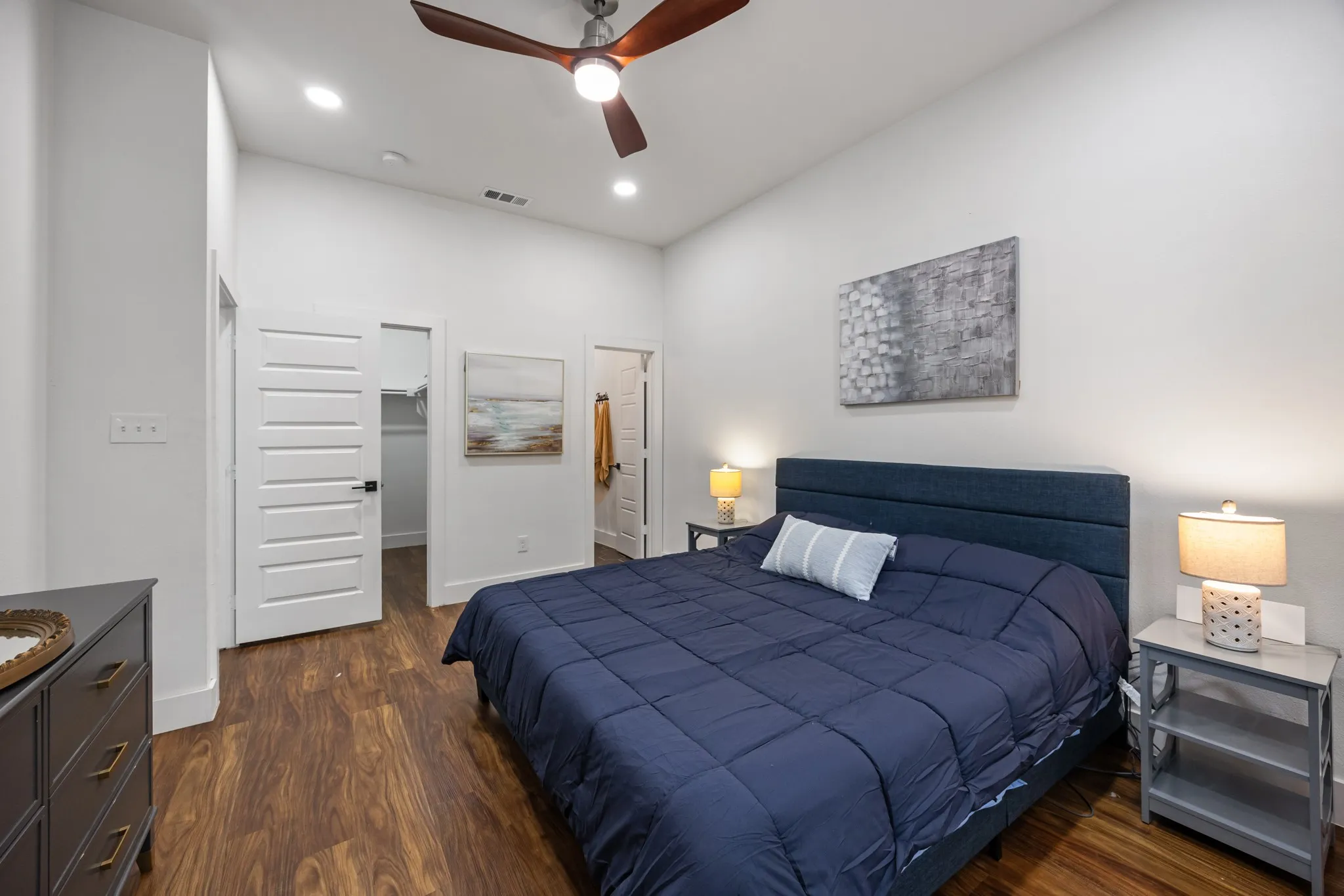 Spacious room featuring wood-finish flooring, white walls, and a ceiling fan with integrated lighting