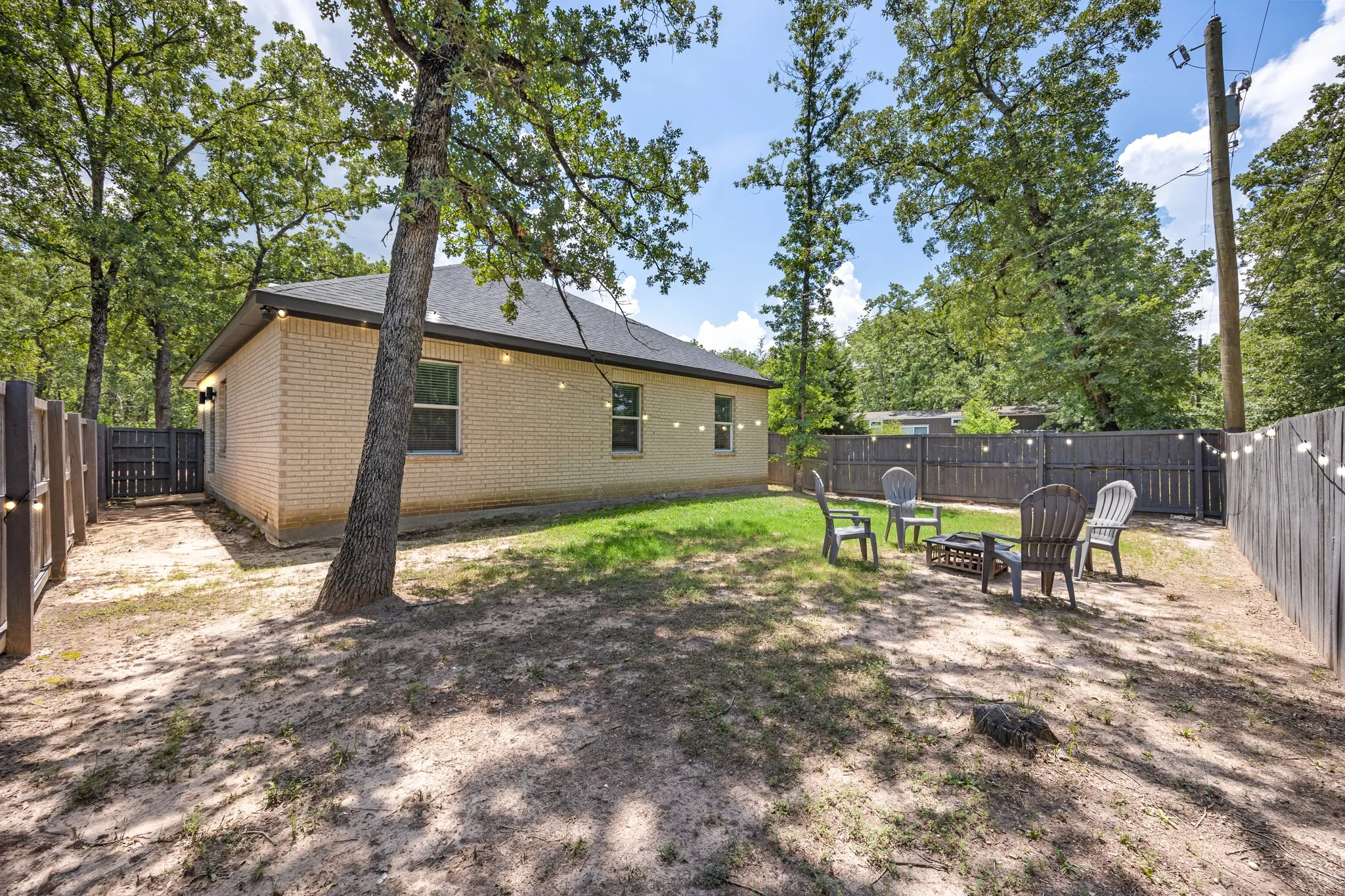 Expansive backyard featuring a partial lawn, mature trees, and privacy fencing