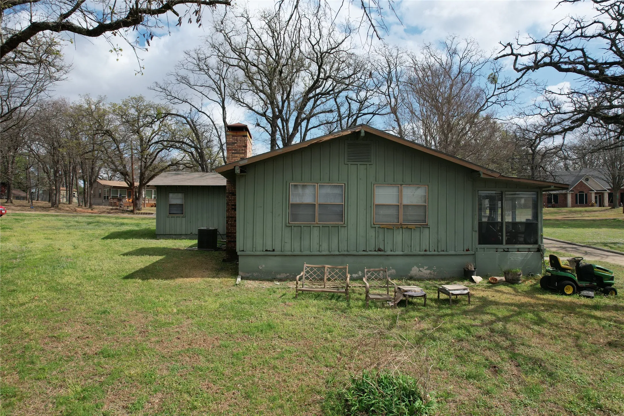 Green siding exterior with a screened porch and brick chimney