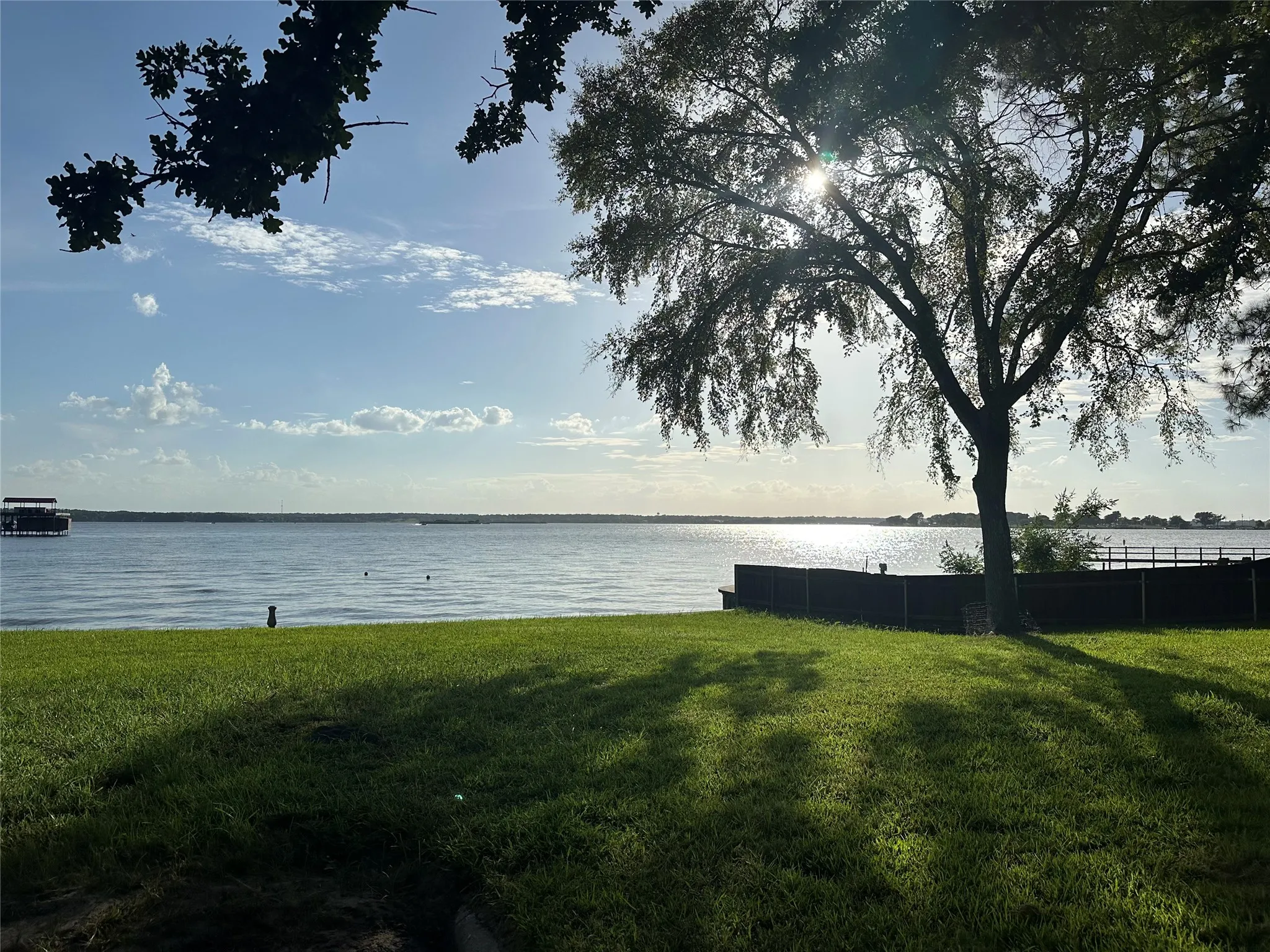 Expansive waterfront property featuring a manicured lawn, mature trees, and substantial water frontage