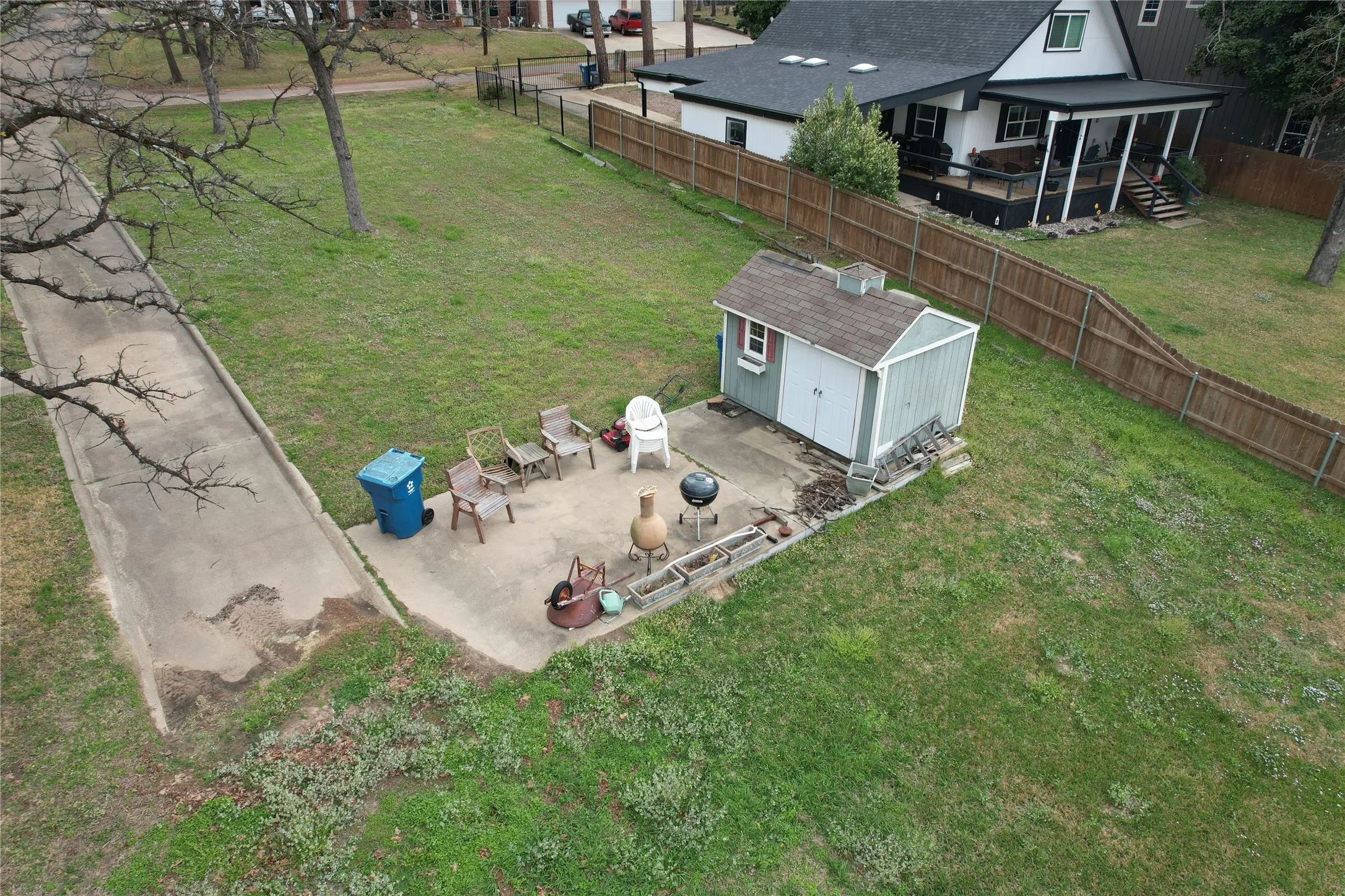 Expansive green space featuring a concrete patio, a dedicated storage shed, and a privacy fence