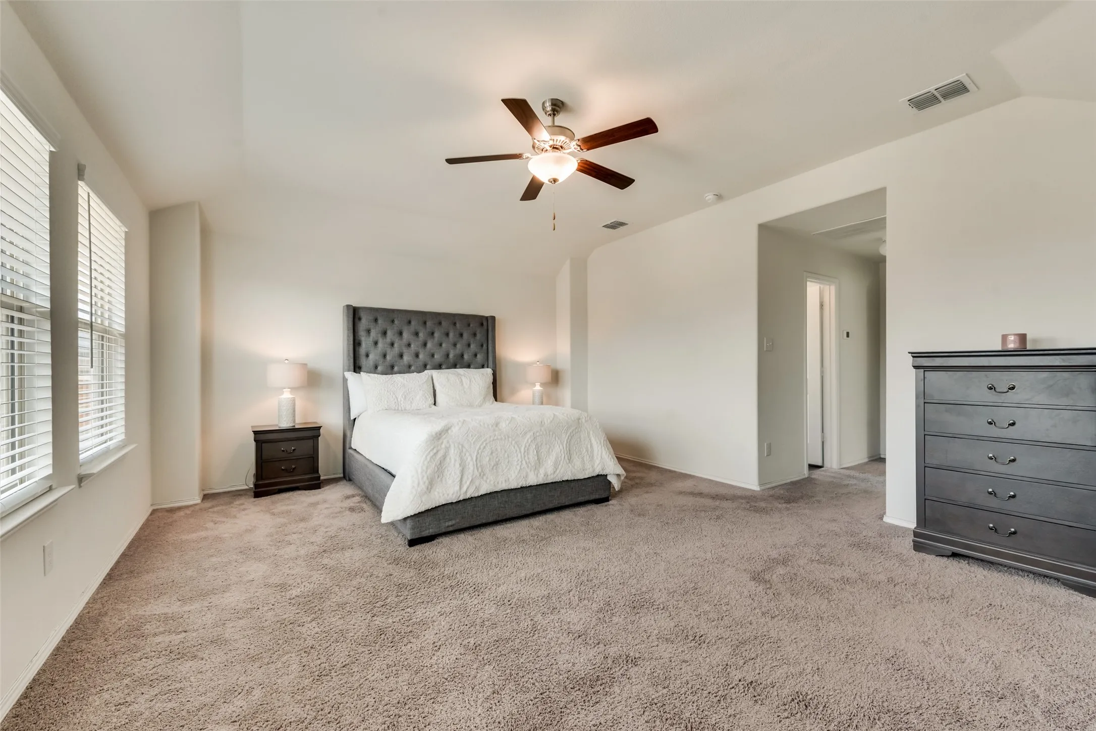 Spacious room featuring vaulted ceilings, neutral-toned wall paint, and plush carpeting