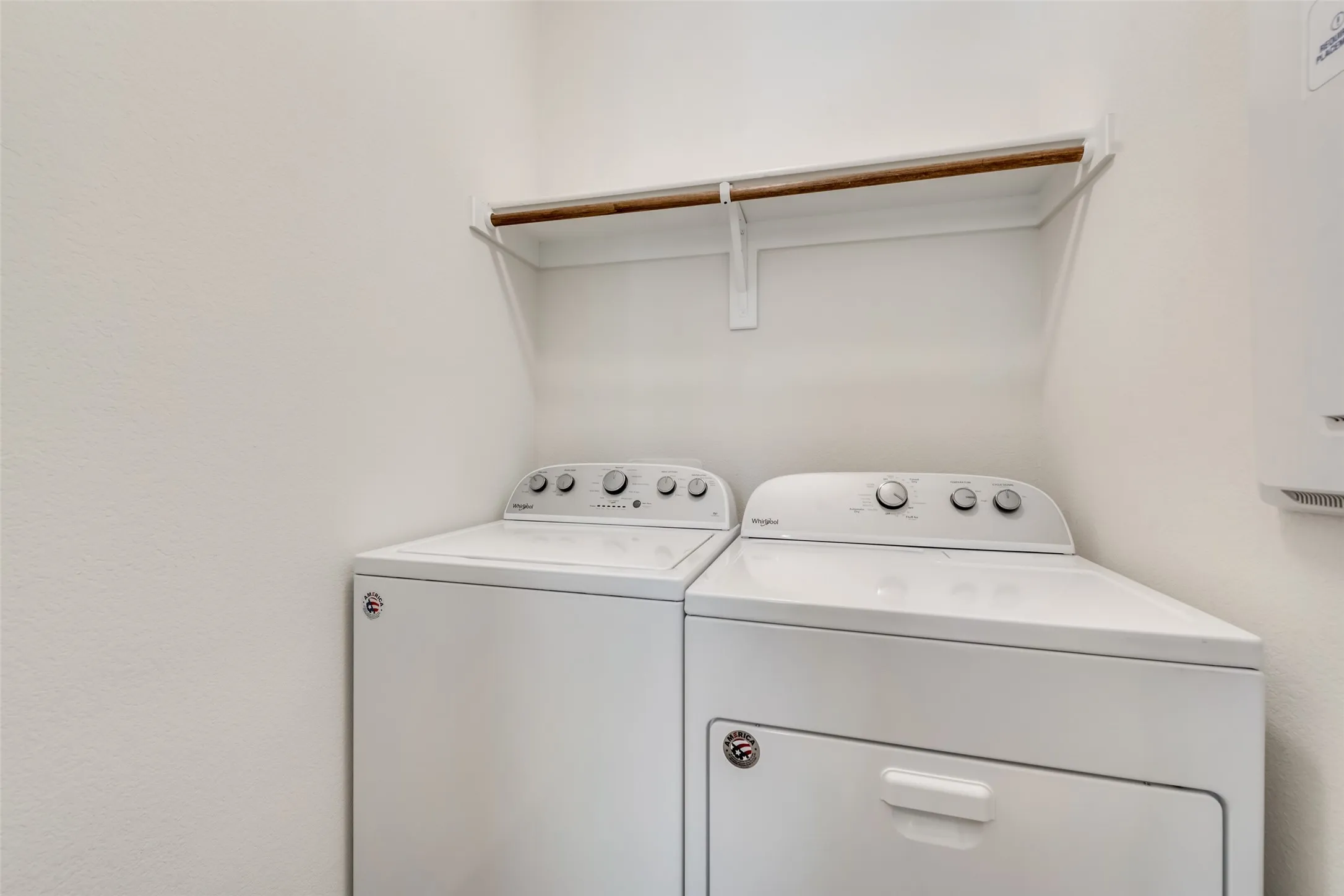 Dedicated laundry area featuring a wall-mounted shelf with a hanging rod