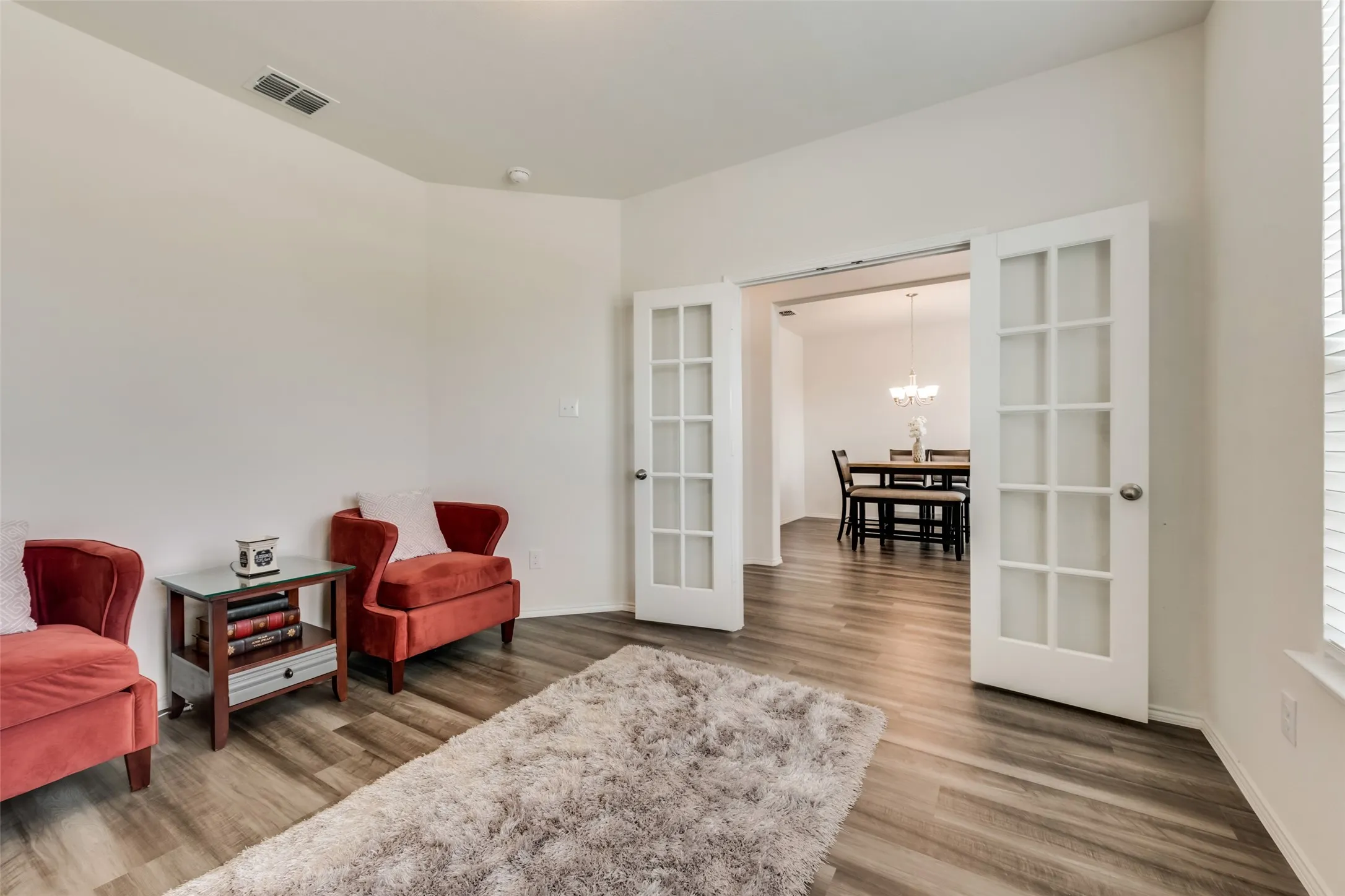 Spacious interior room featuring wood-finish flooring, light-toned walls, and high ceilings