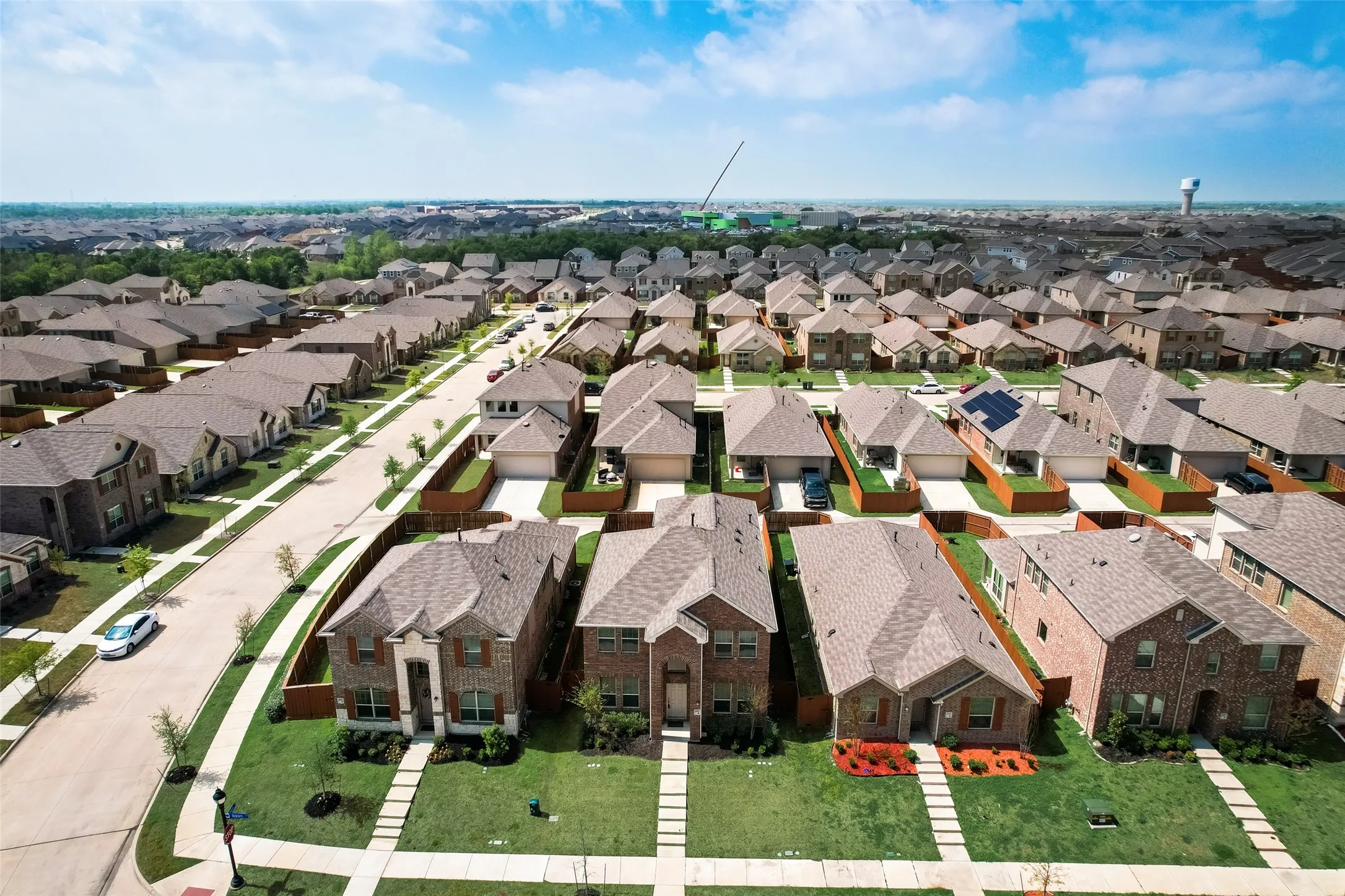Aerial perspective of a developed residential neighborhood featuring varied single-family homes with uniform rooflines and well-maintained lawns