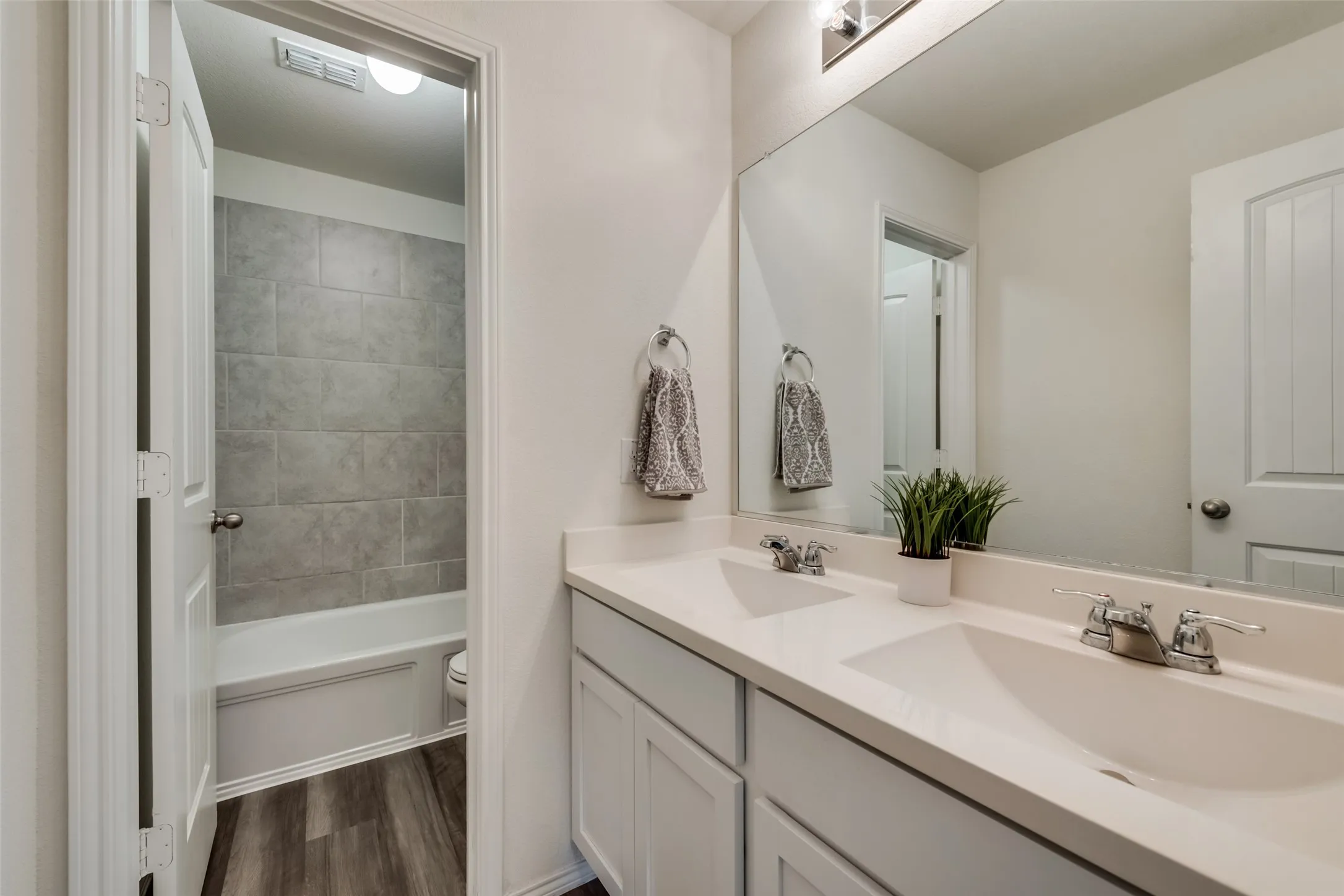 Double vanity with integrated sinks, chrome fixtures, and a large wall-mounted mirror