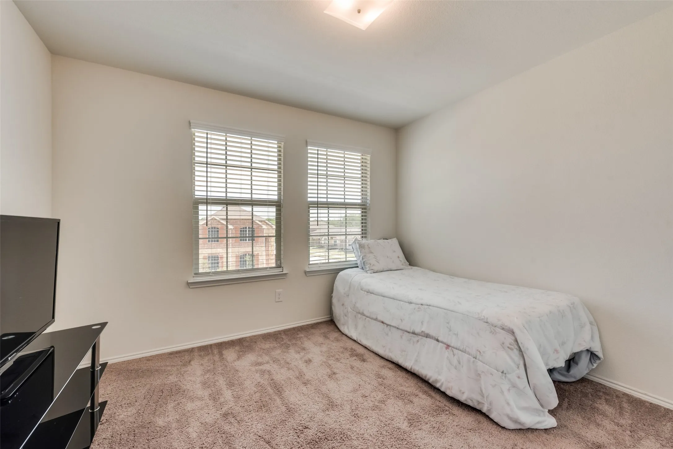 Room featuring two windows with horizontal blinds, neutral wall paint, and brown carpeting