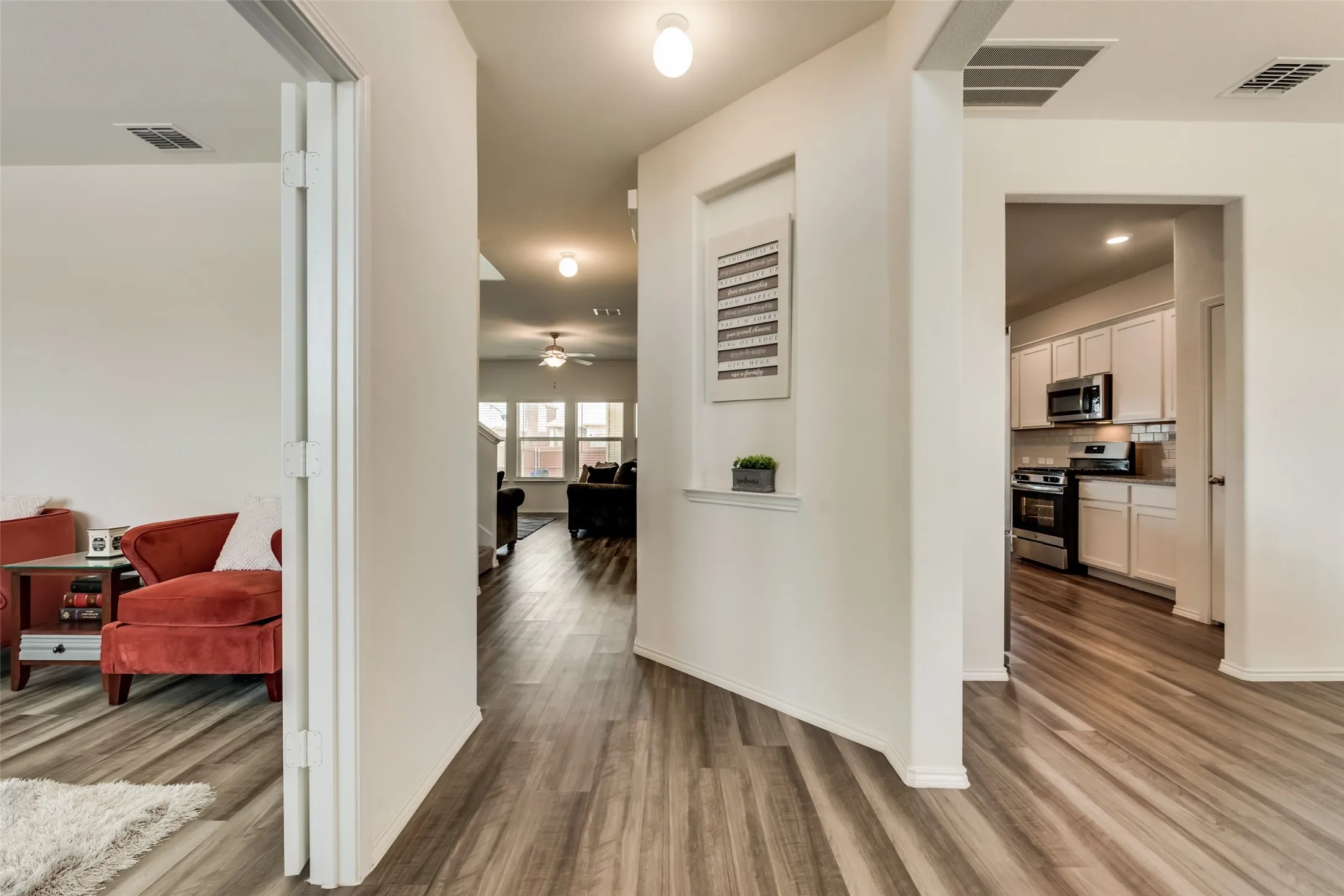 Open concept living space featuring wood-finish flooring throughout, recessed lighting, and a built-in kitchen with white cabinetry and stainless steel appliances
