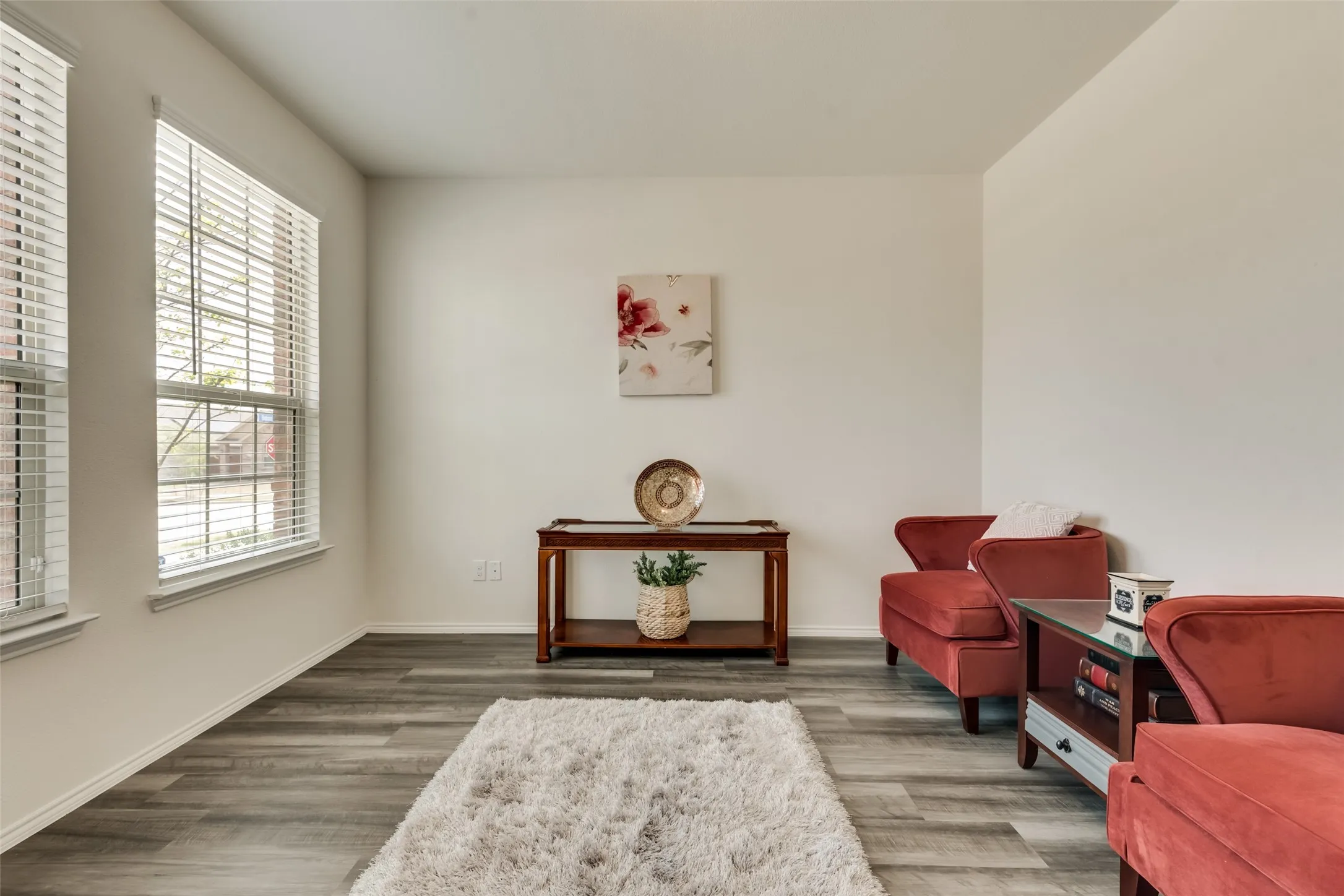 Living area featuring wood-finish flooring and two large windows with blinds