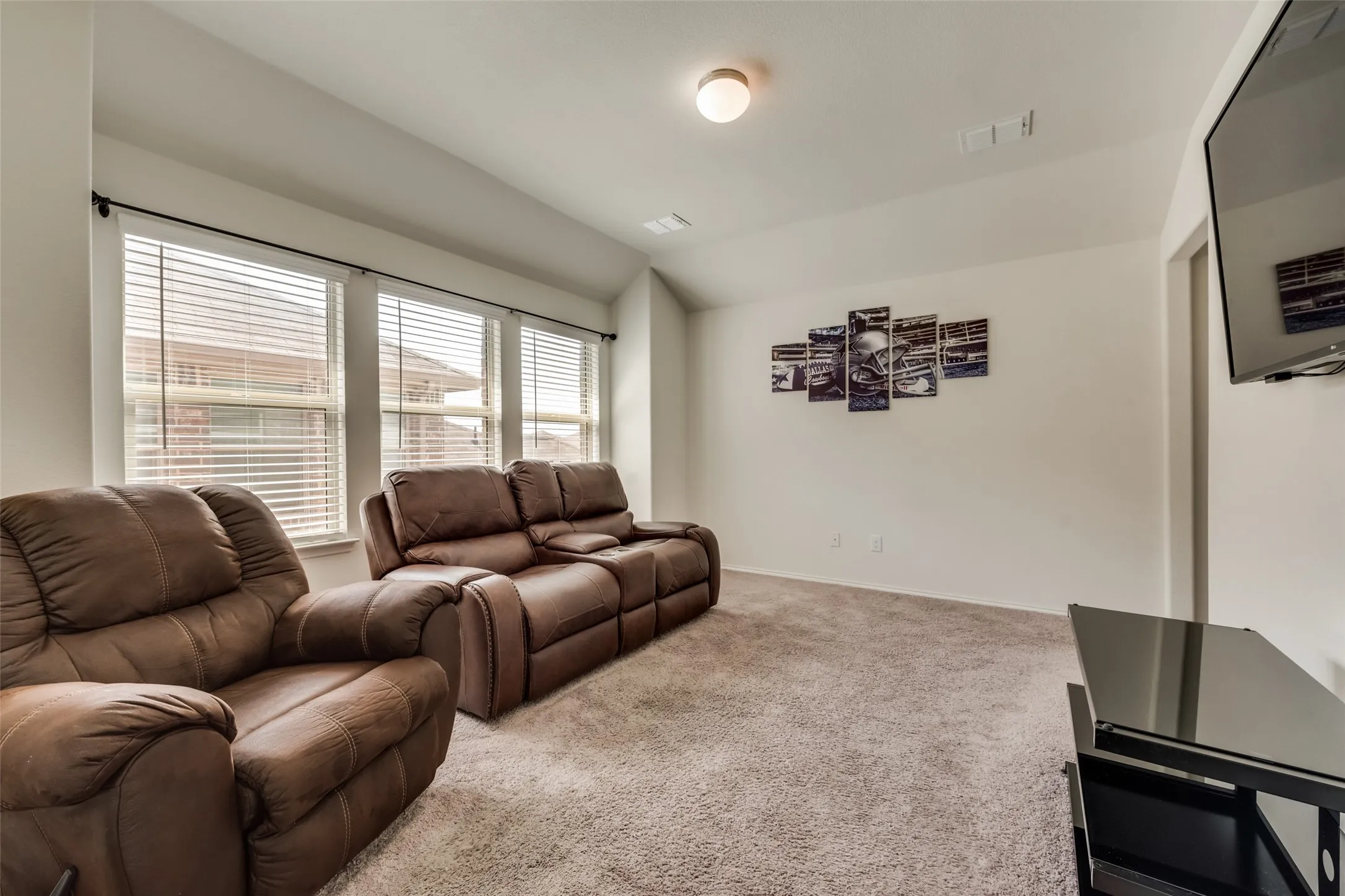 Carpeted secondary living space with white walls and three windows
