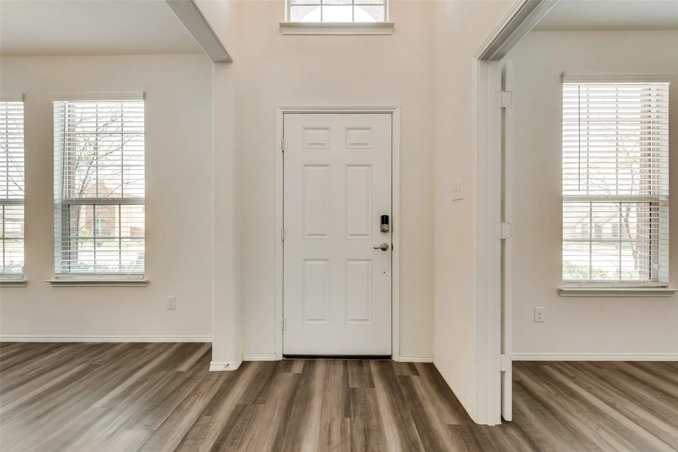 Entrance foyer featuring a paneled door with smart lock, wood-finish flooring, transom window, and ample natural light from two side windows