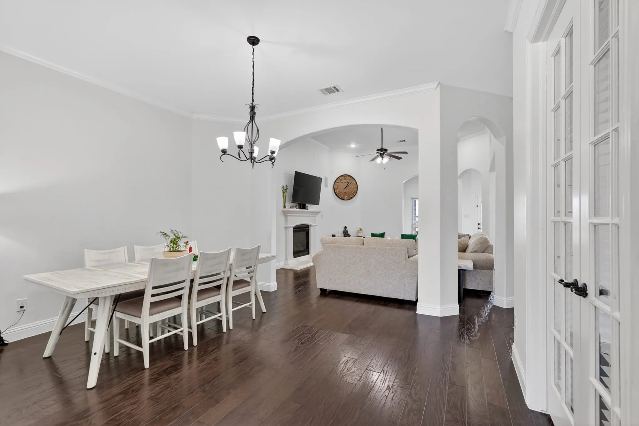 Expansive room featuring dark wood-finish flooring, white crown molding, and a five-light chandelier