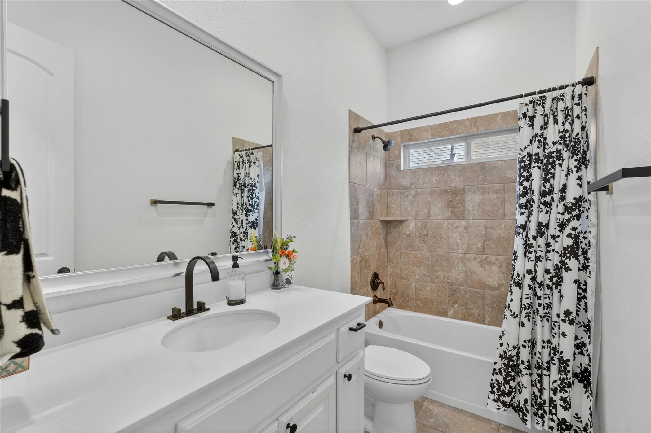Bathroom featuring a white vanity with an undermount sink, a large framed mirror, and matte black hardware