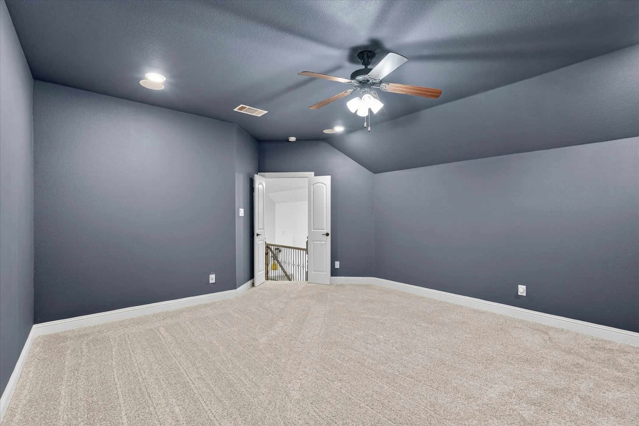Spacious room featuring vaulted ceilings, recessed lighting, a ceiling fan, plush carpet flooring, and crisp white baseboards