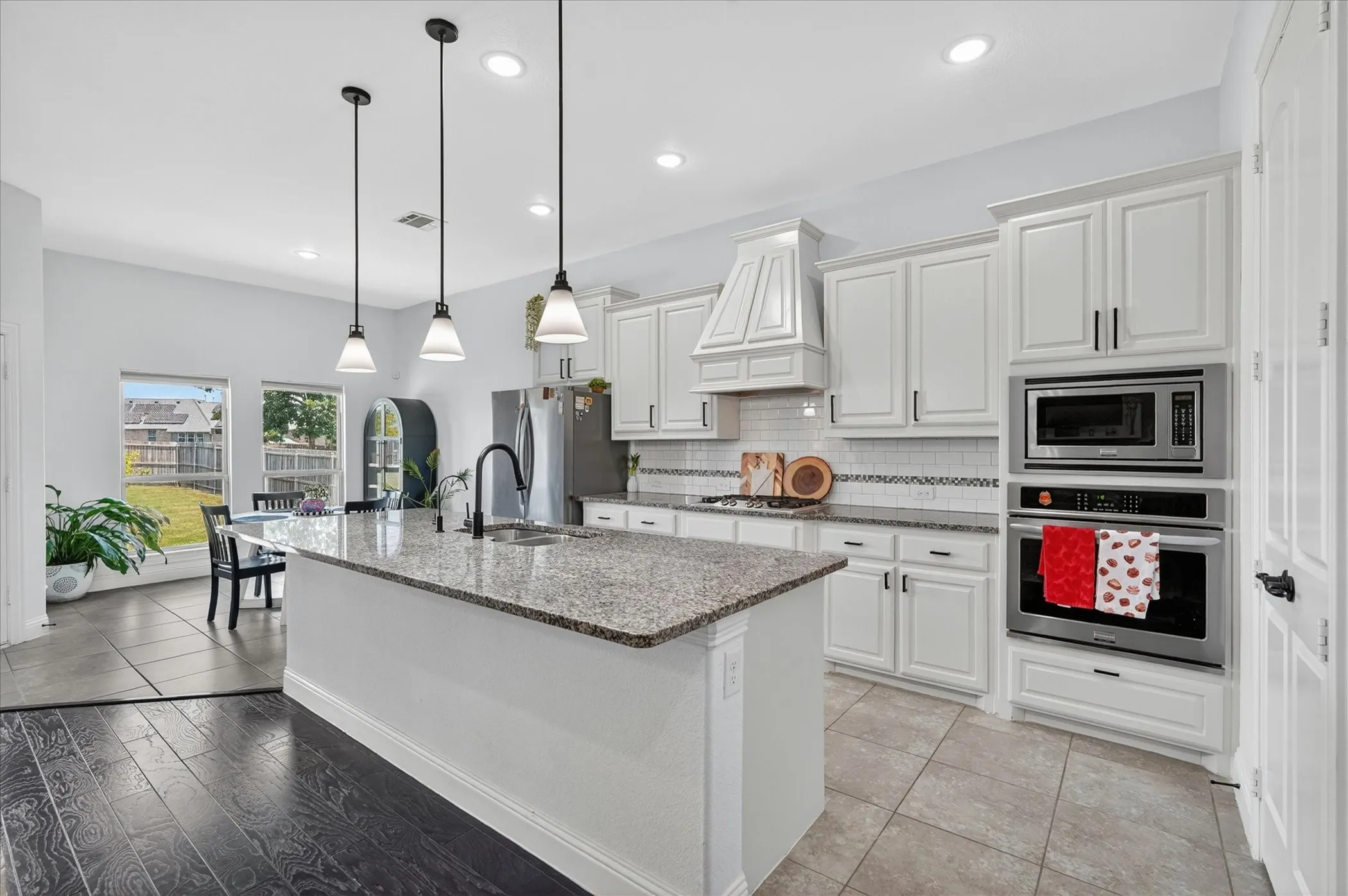 Kitchen island featuring a granite countertop, undermount sink, and three pendant lights