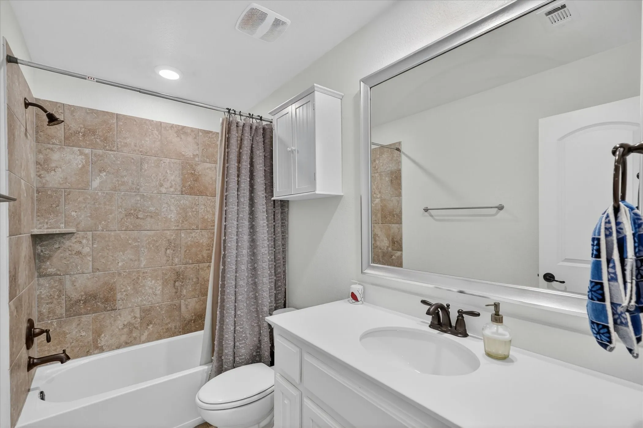 Bathroom featuring a single vanity with a white countertop, an undermount sink, and dark bronze-finish hardware