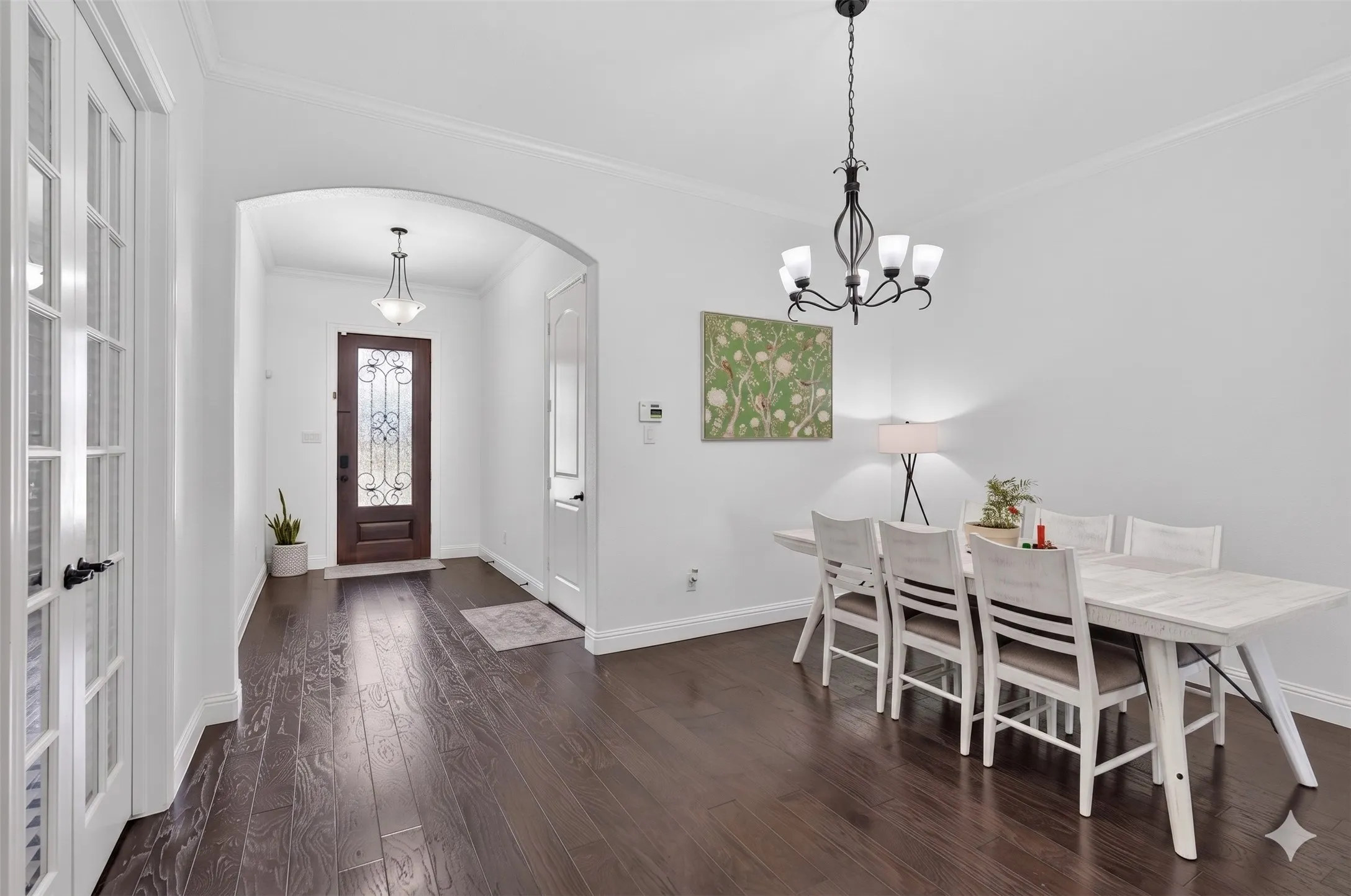 Entryway featuring dark wood-finish flooring, an arched doorway, and a decorative front door with leaded glass