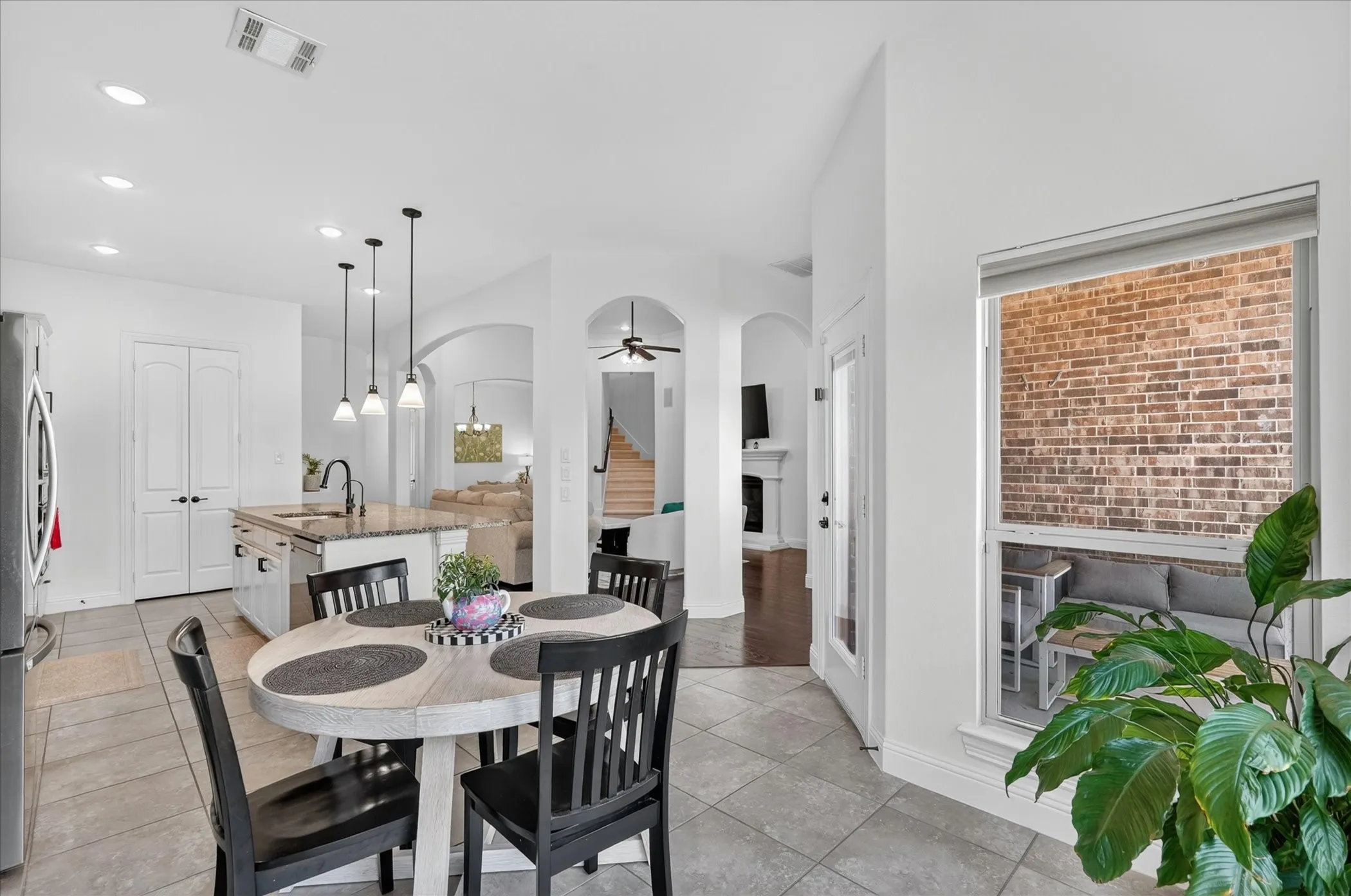 Open concept kitchen featuring a central island with granite countertops, pendant lighting, and tiled flooring