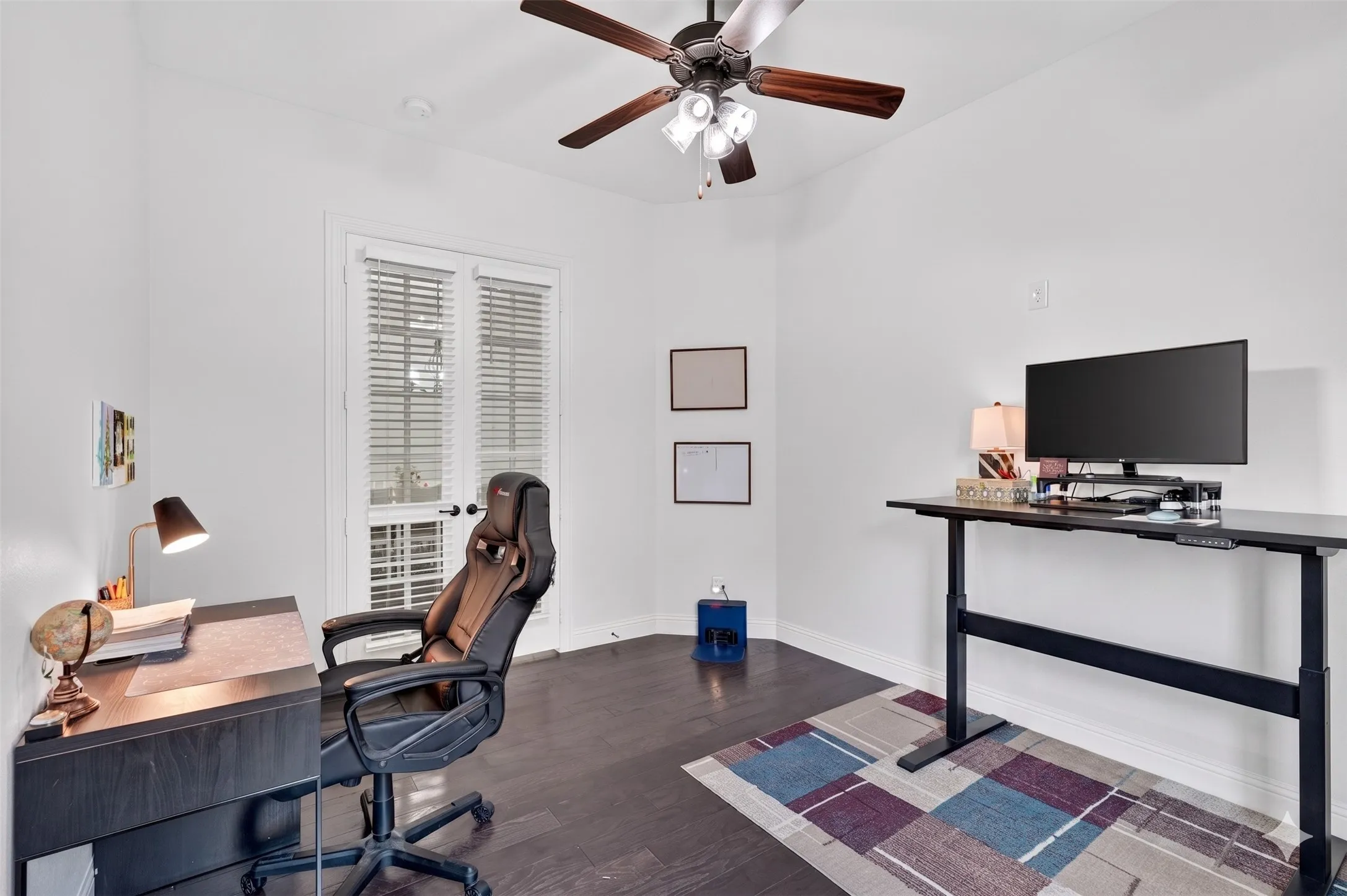Room featuring wood-finish flooring, white walls, and a ceiling fan with integrated lighting