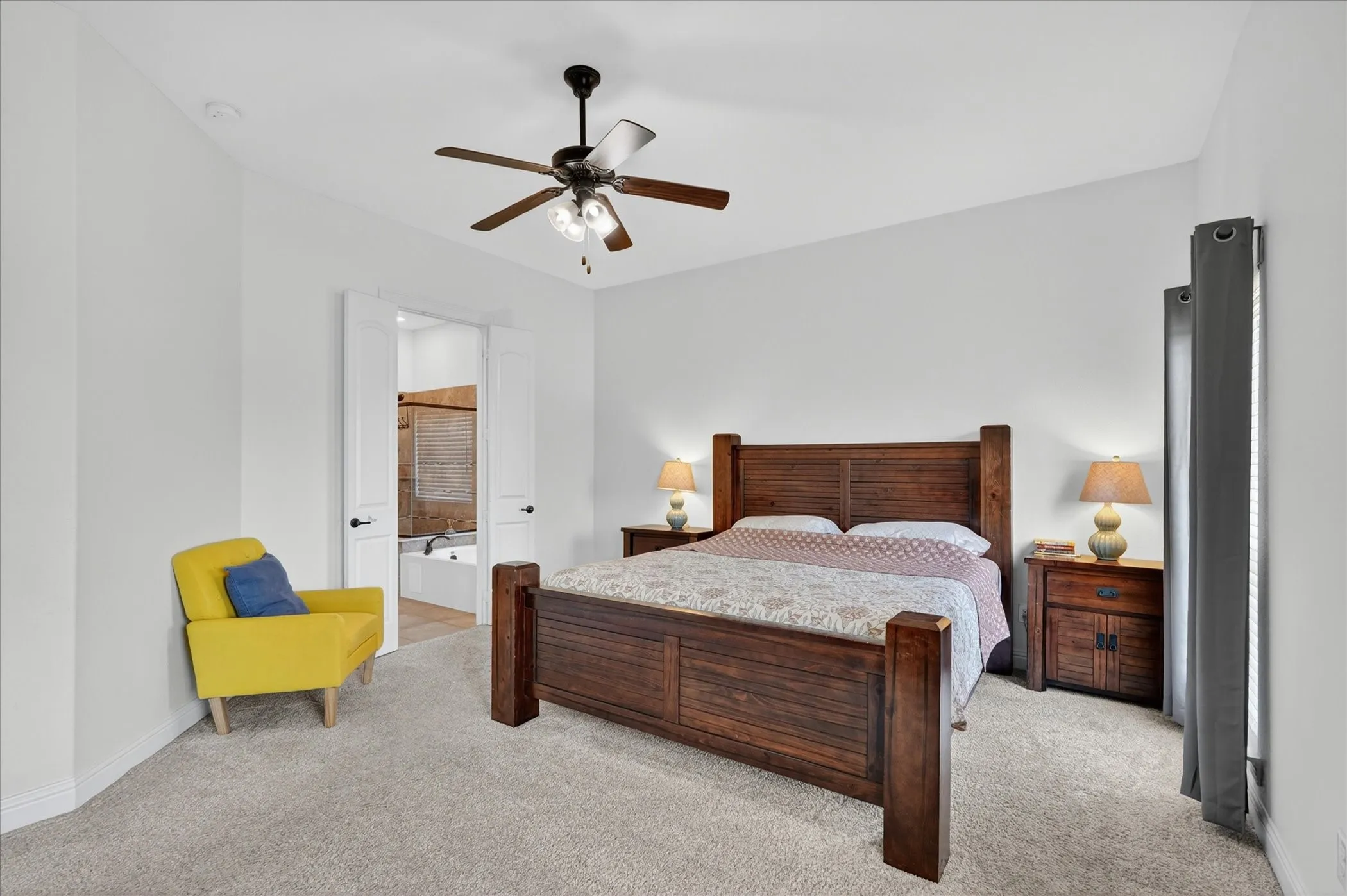 Carpeted room with a ceiling fan, white walls, and a doorway revealing a built-in bathtub