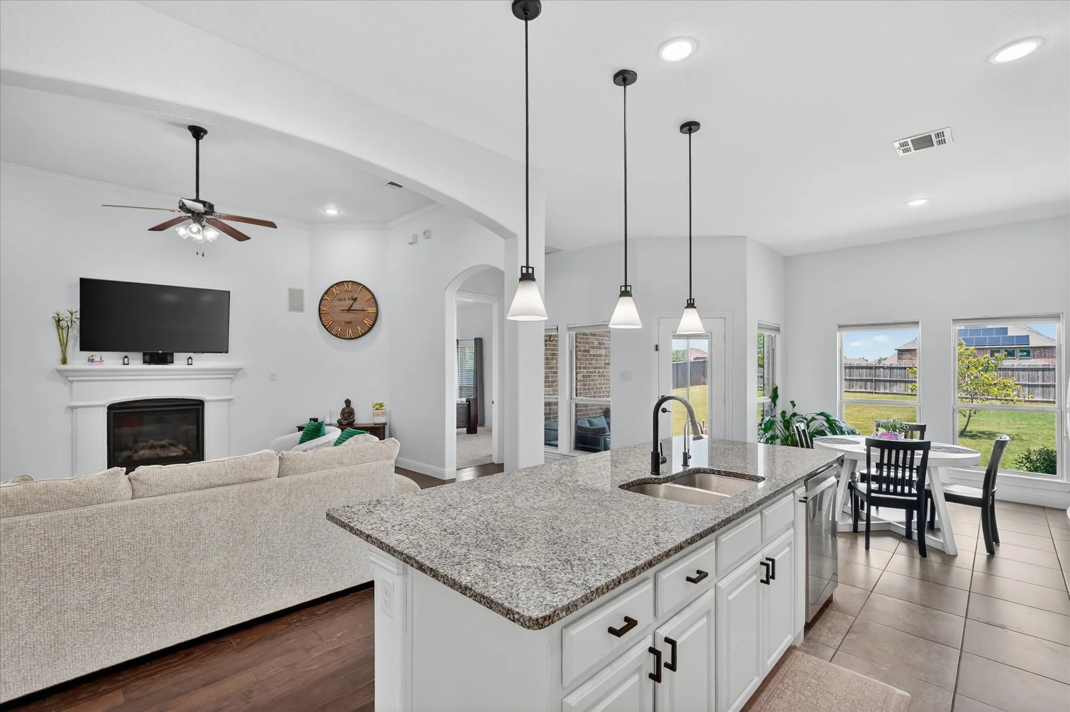 Open-concept kitchen featuring an island with granite countertops and pendant lighting, stainless steel appliances, and tile flooring