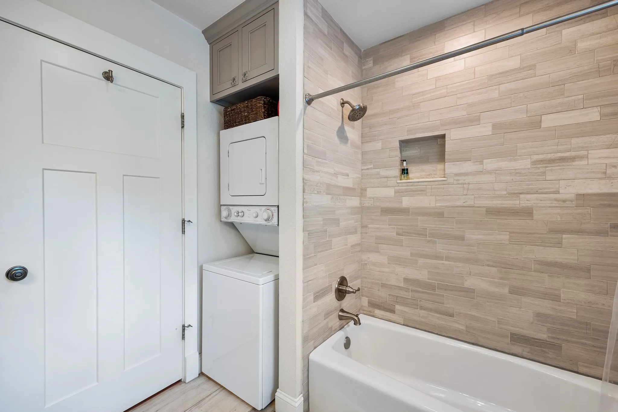Bathroom featuring a white bathtub with brushed nickel fixtures and a tiled shower surround with a recessed niche