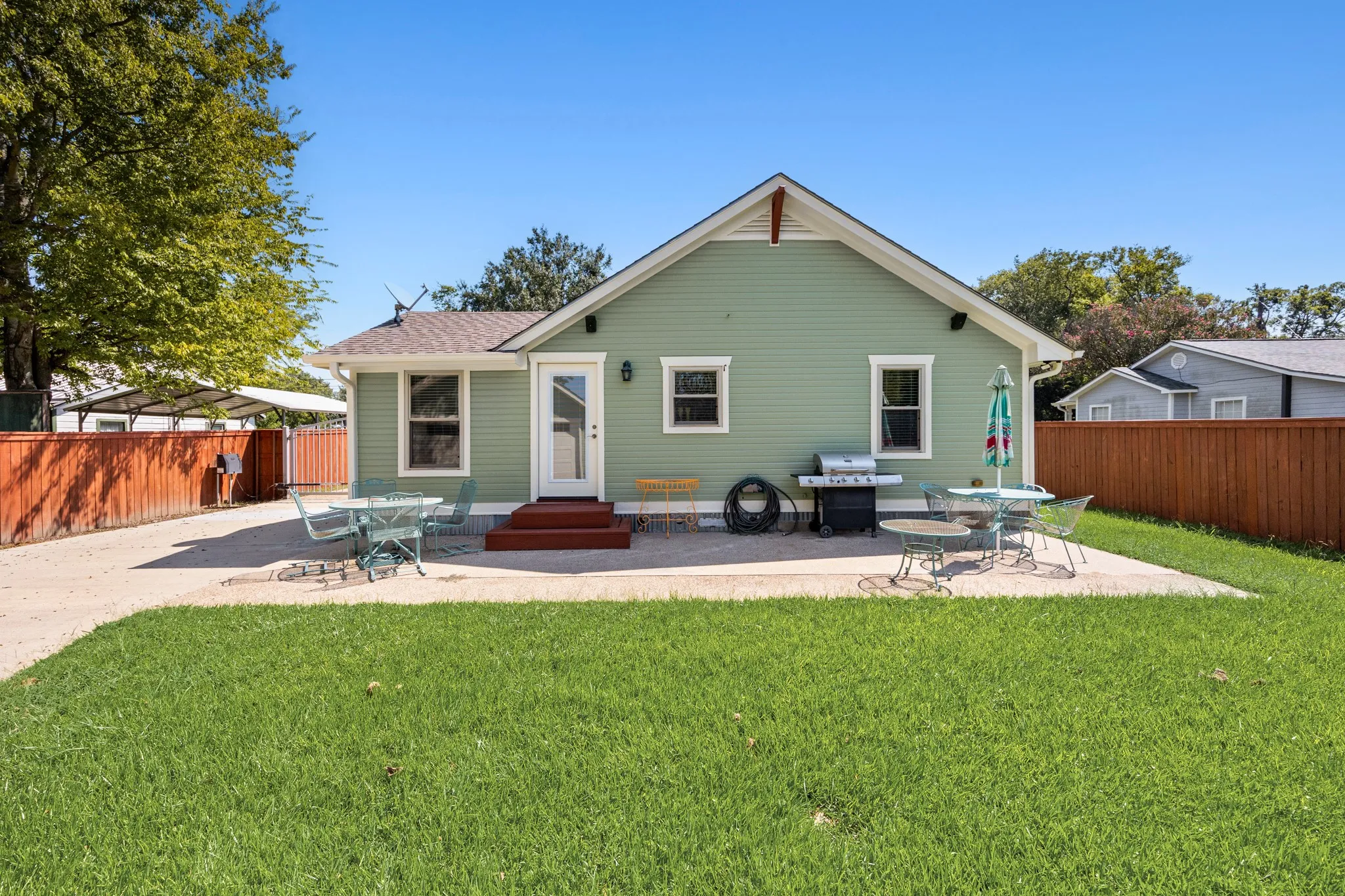 Large backyard featuring a spacious paved patio, a manicured lawn, and a privacy fence