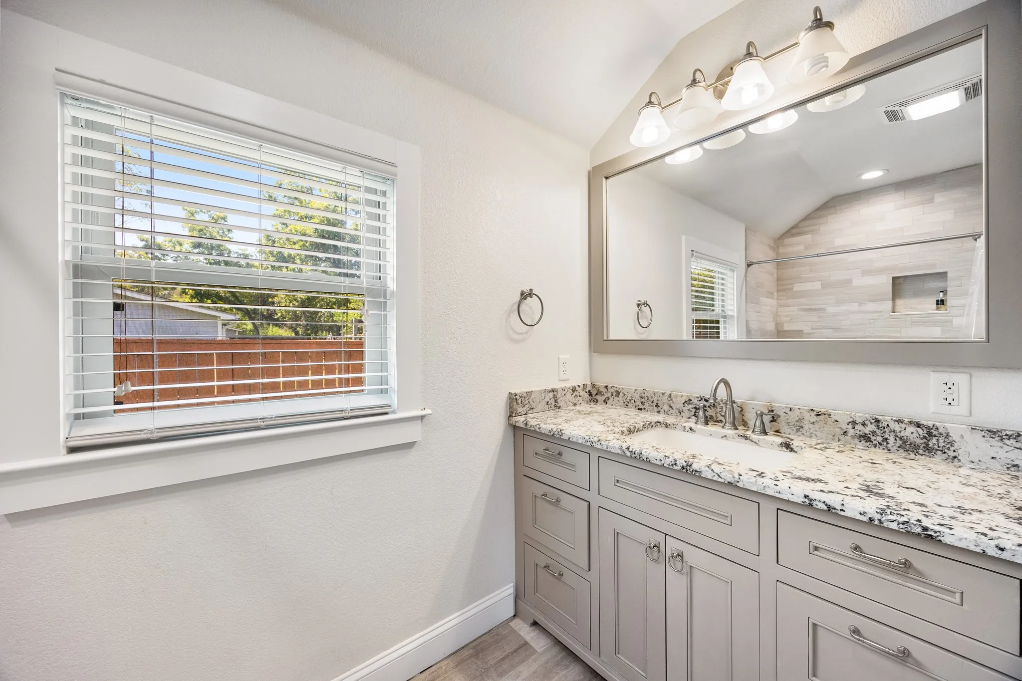 Bathroom vanity featuring a speckled countertop, undermount sink, and brushed nickel faucet