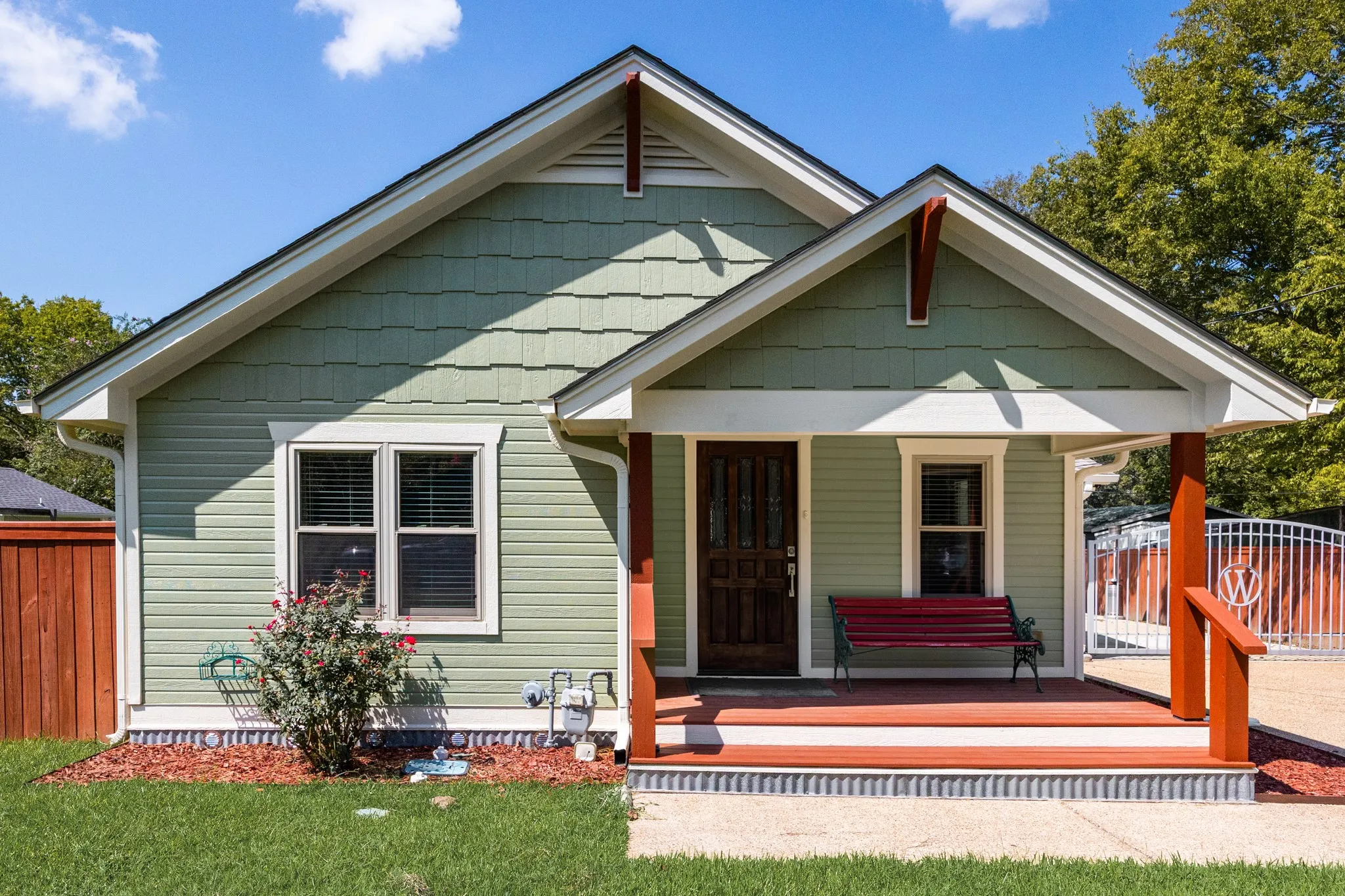 Gable roofline home featuring green horizontal siding and decorative shingle siding accents