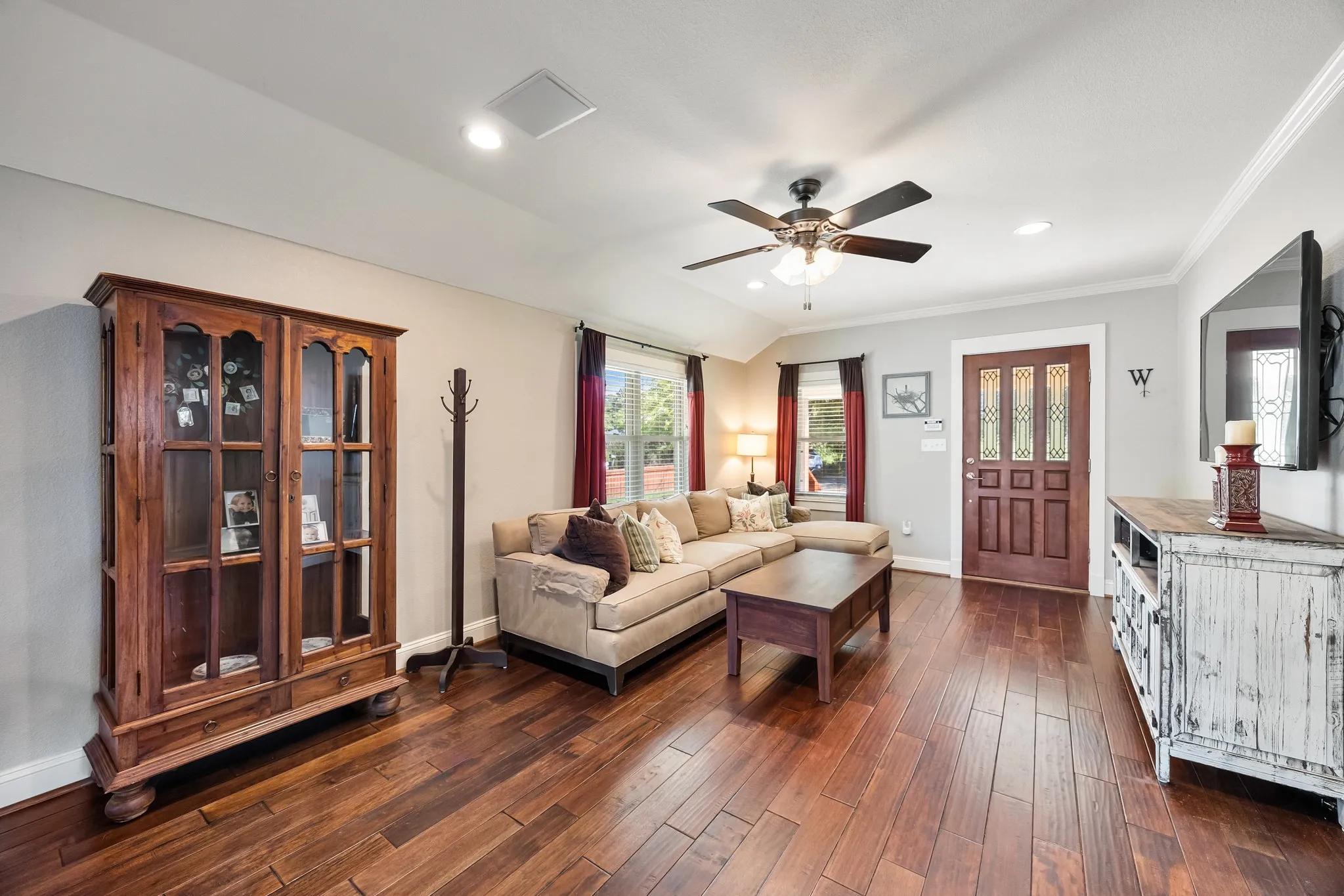 Living area featuring rich wood-finish flooring, a decorative front entry door with glass inserts, recessed lighting, crown molding, and a ceiling fan