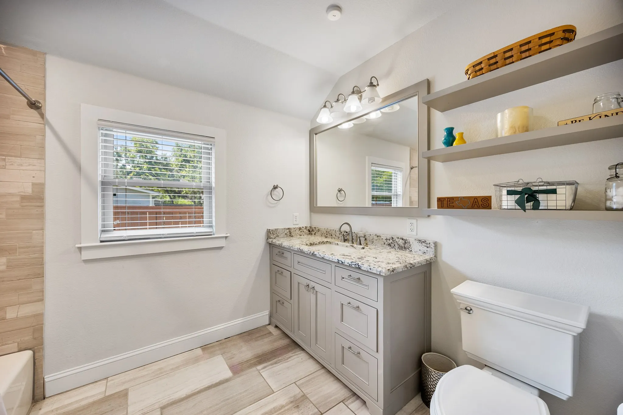 Bathroom featuring a single vanity with stone countertop, undermount sink, and polished chrome faucet