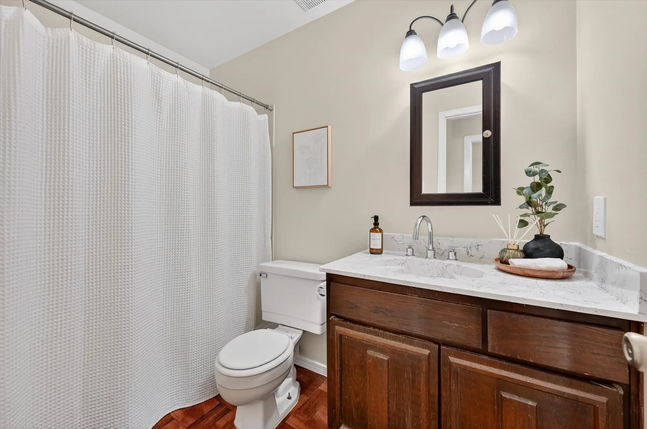 Bathroom featuring a dark wood-finish vanity with a light-colored countertop, chrome faucet, and a wall-mounted mirror
