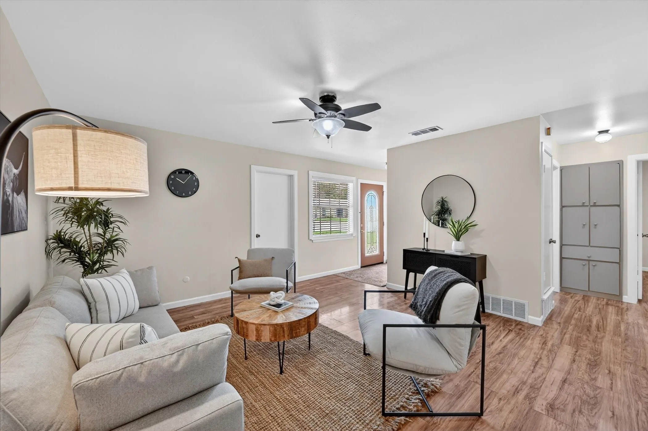 Open-concept living space featuring wood-finish flooring, a contemporary ceiling fan, and light neutral wall tones