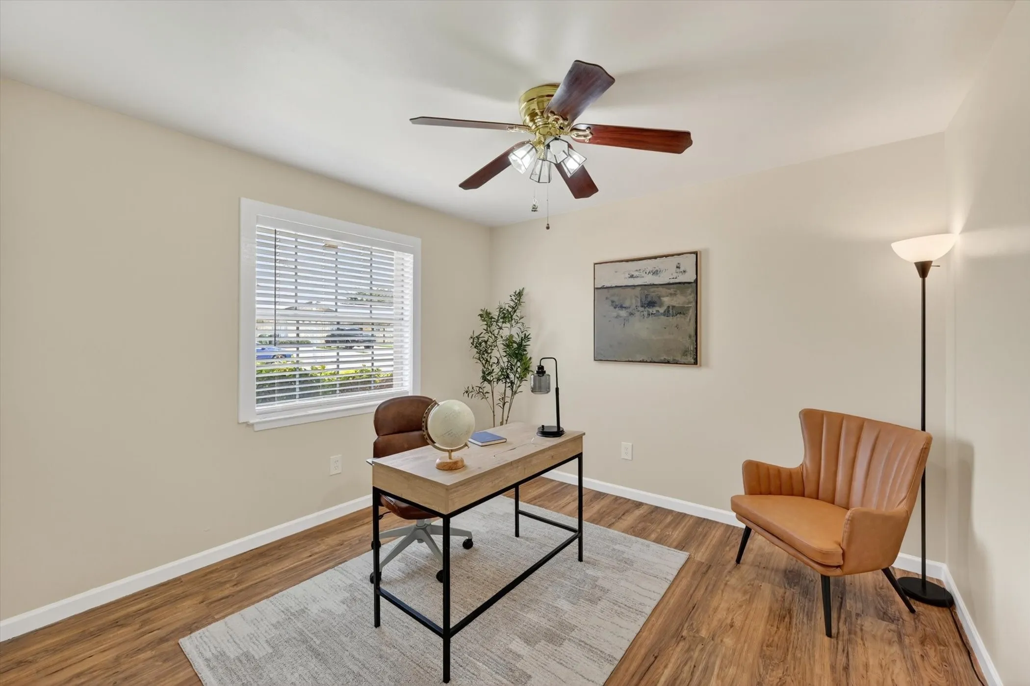 Room with wood-finish flooring, a ceiling fan with integrated lighting, and a window with blinds
