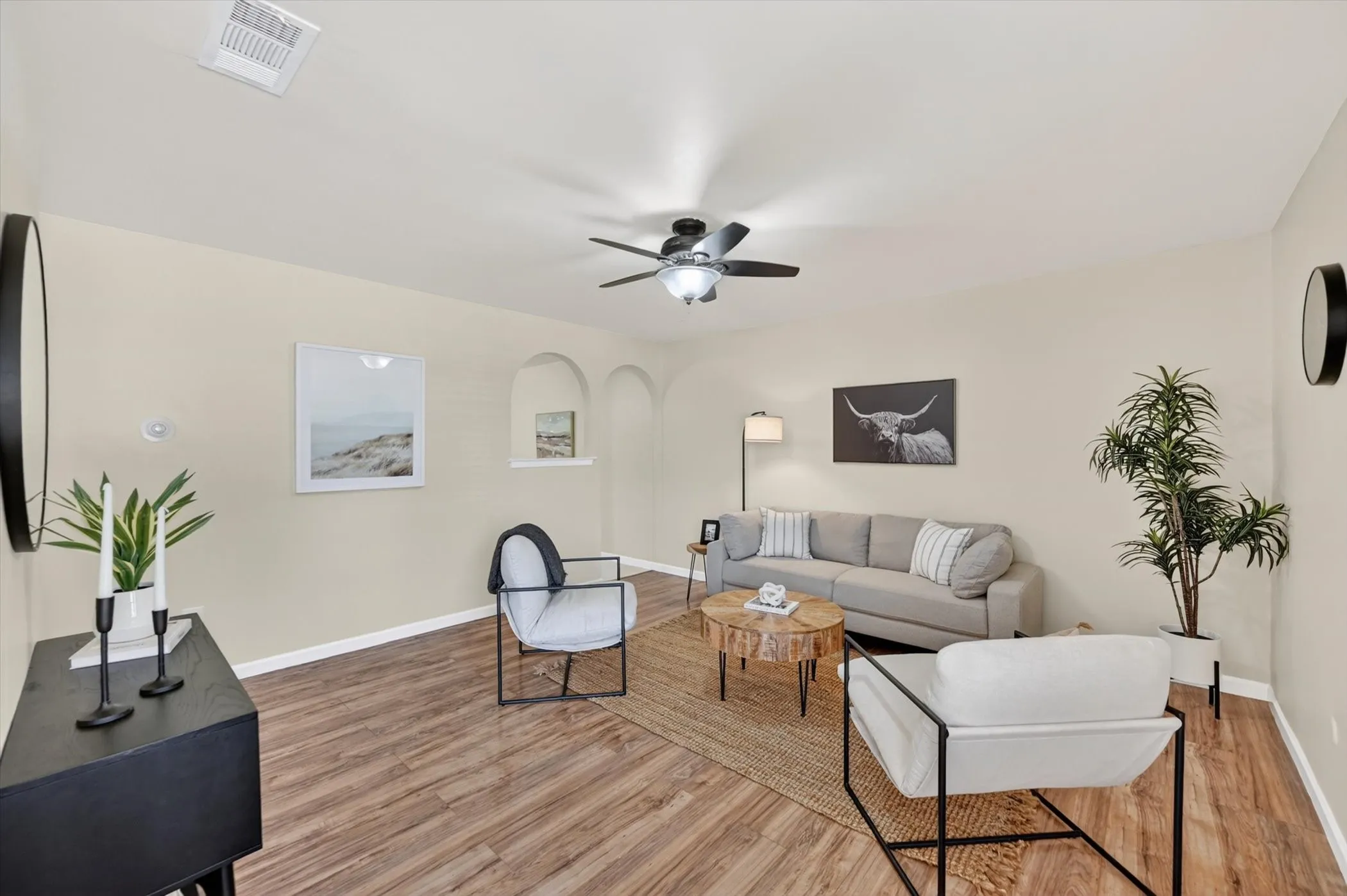 Spacious living area featuring wood-finish flooring, neutral wall tones, and recessed arched wall niches