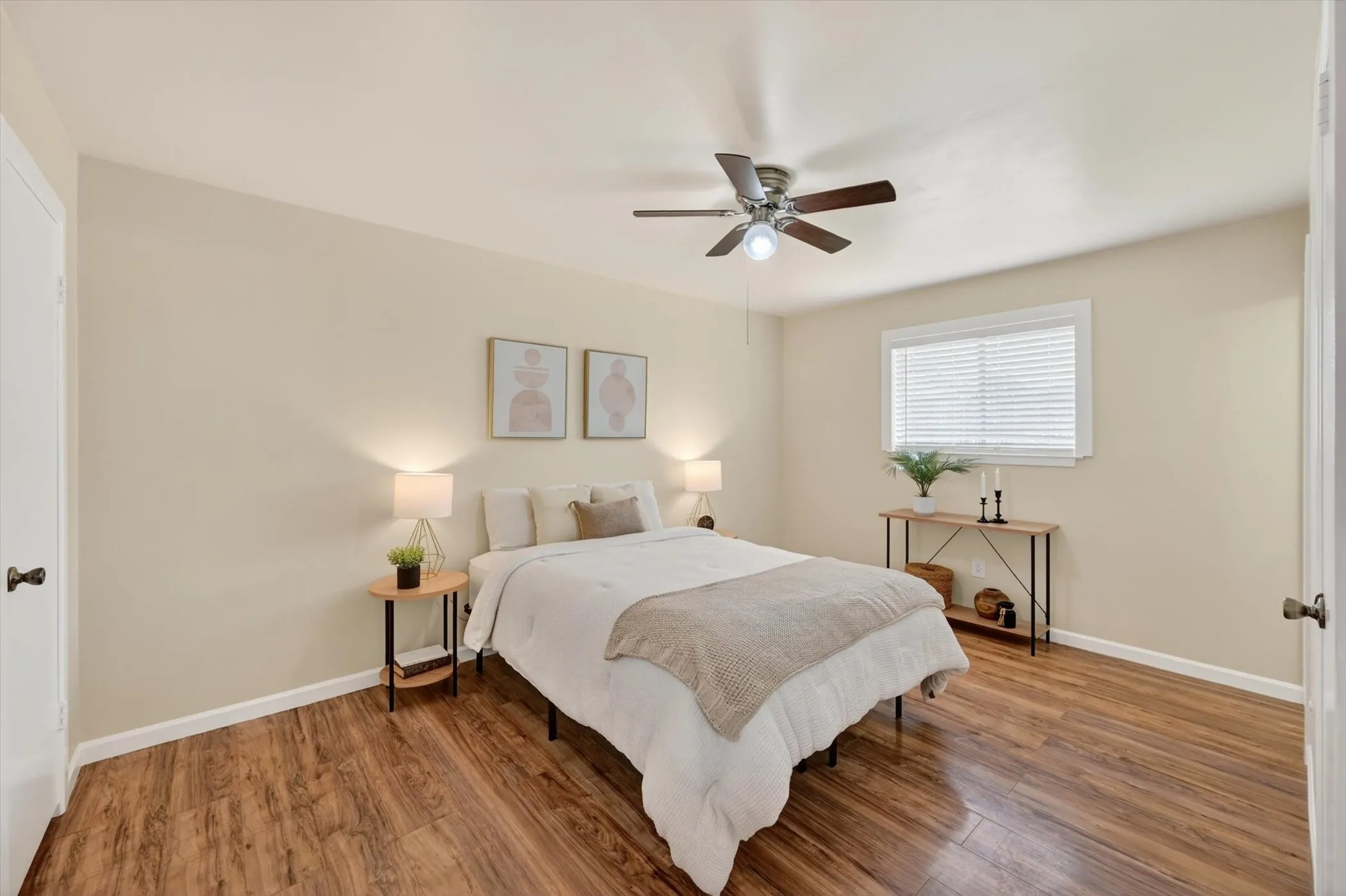 Bedroom featuring wood-finish flooring, a ceiling fan with integrated lighting, a window with horizontal blinds, and neutral wall tones