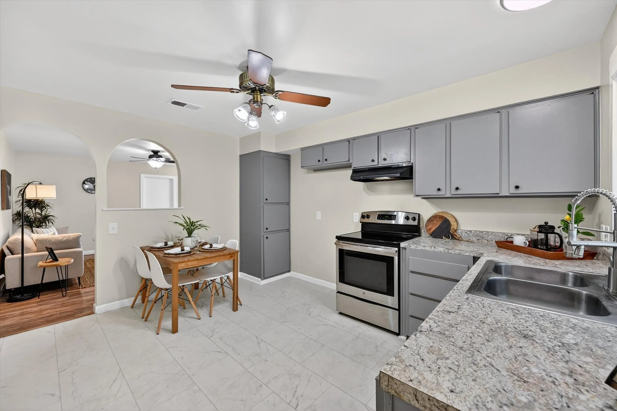 Kitchen featuring stainless steel appliances, dual basin sink, light-toned countertops, and grey cabinetry