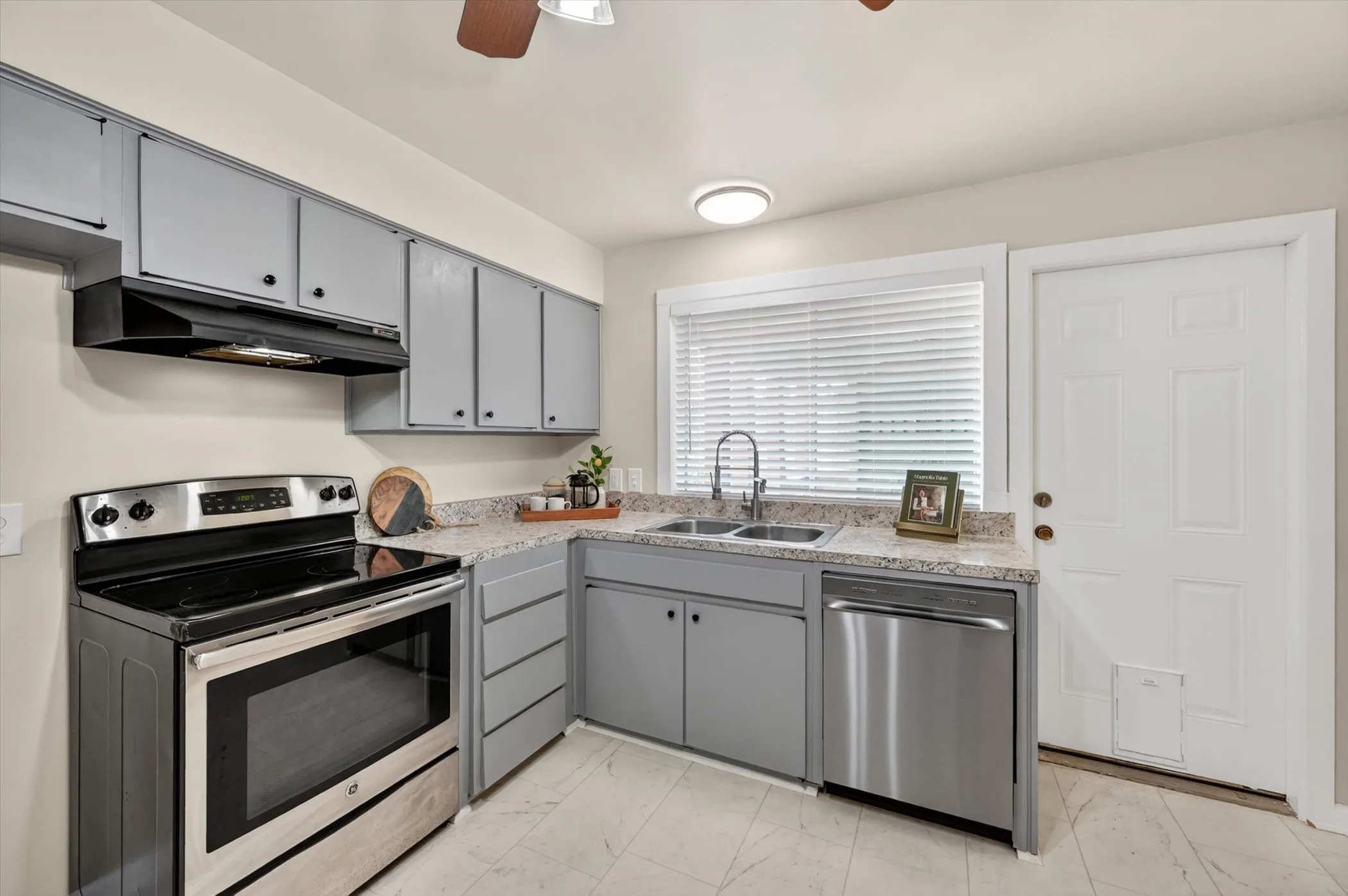 Kitchen featuring gray cabinetry, light-toned countertops, and a white paneled door
