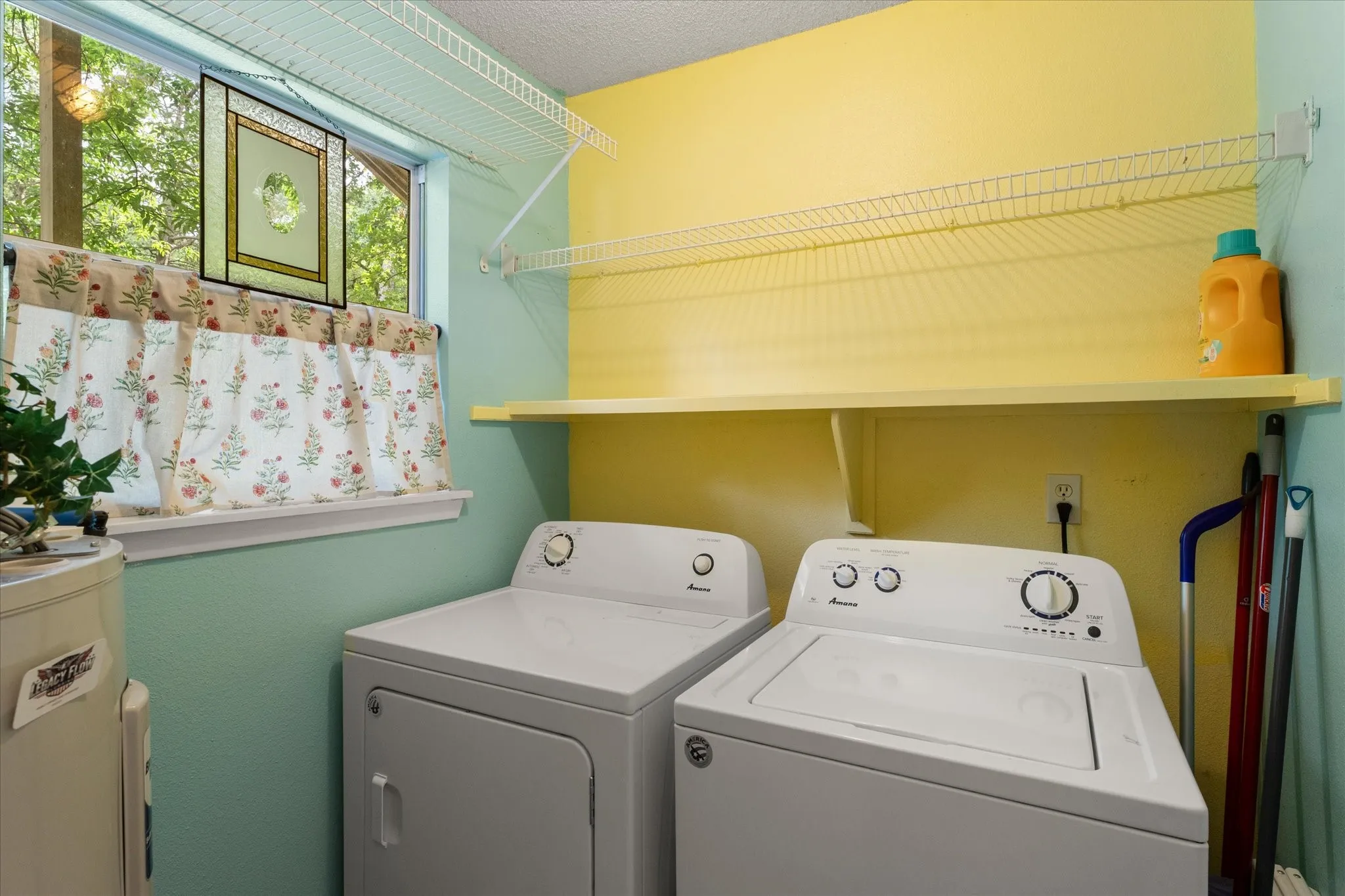 Dedicated laundry area featuring a washer and dryer, an overhead shelving unit, and a built-in wall shelf