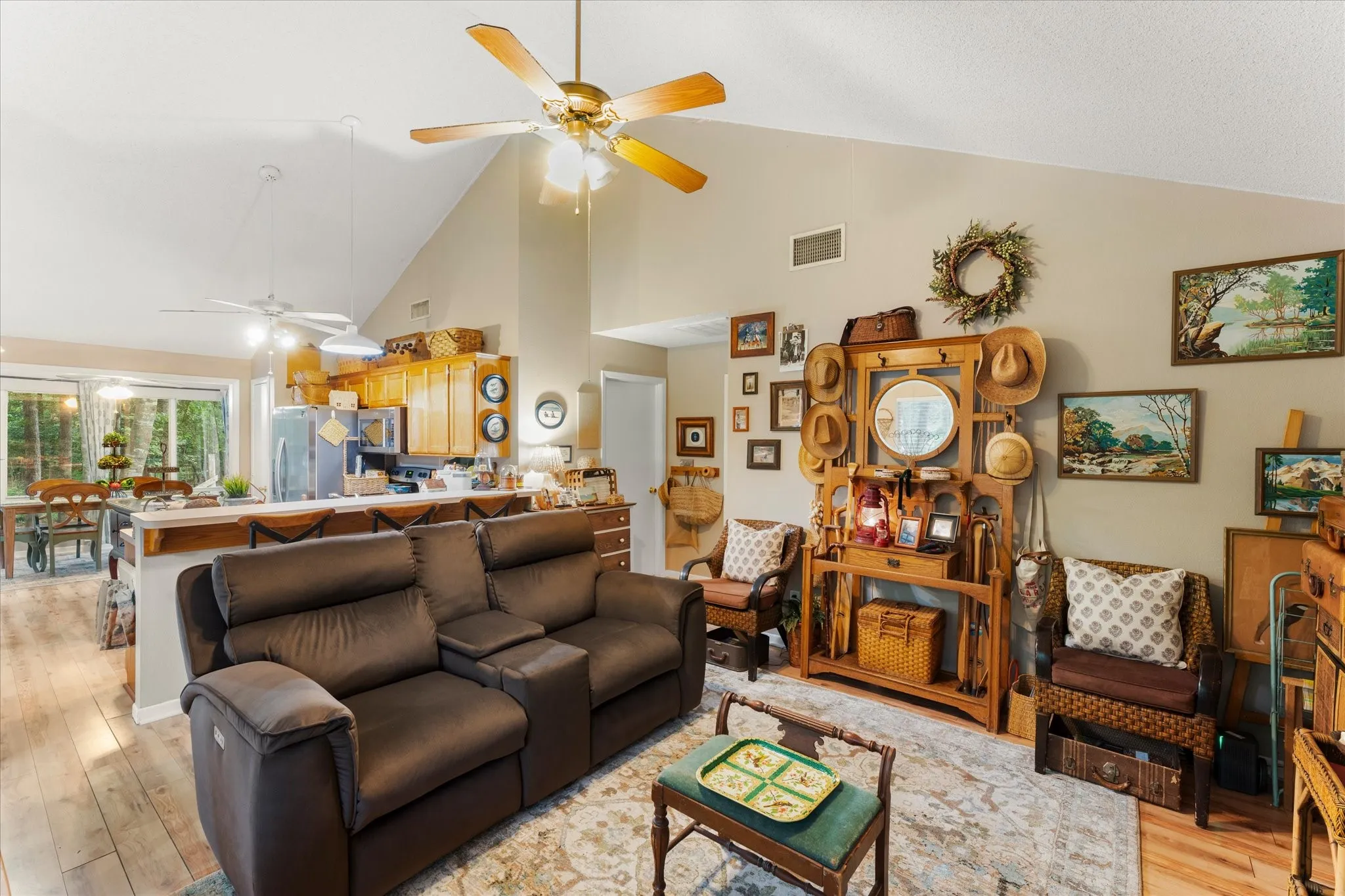 Spacious living area featuring vaulted ceilings, wood-finish flooring, and a ceiling fan