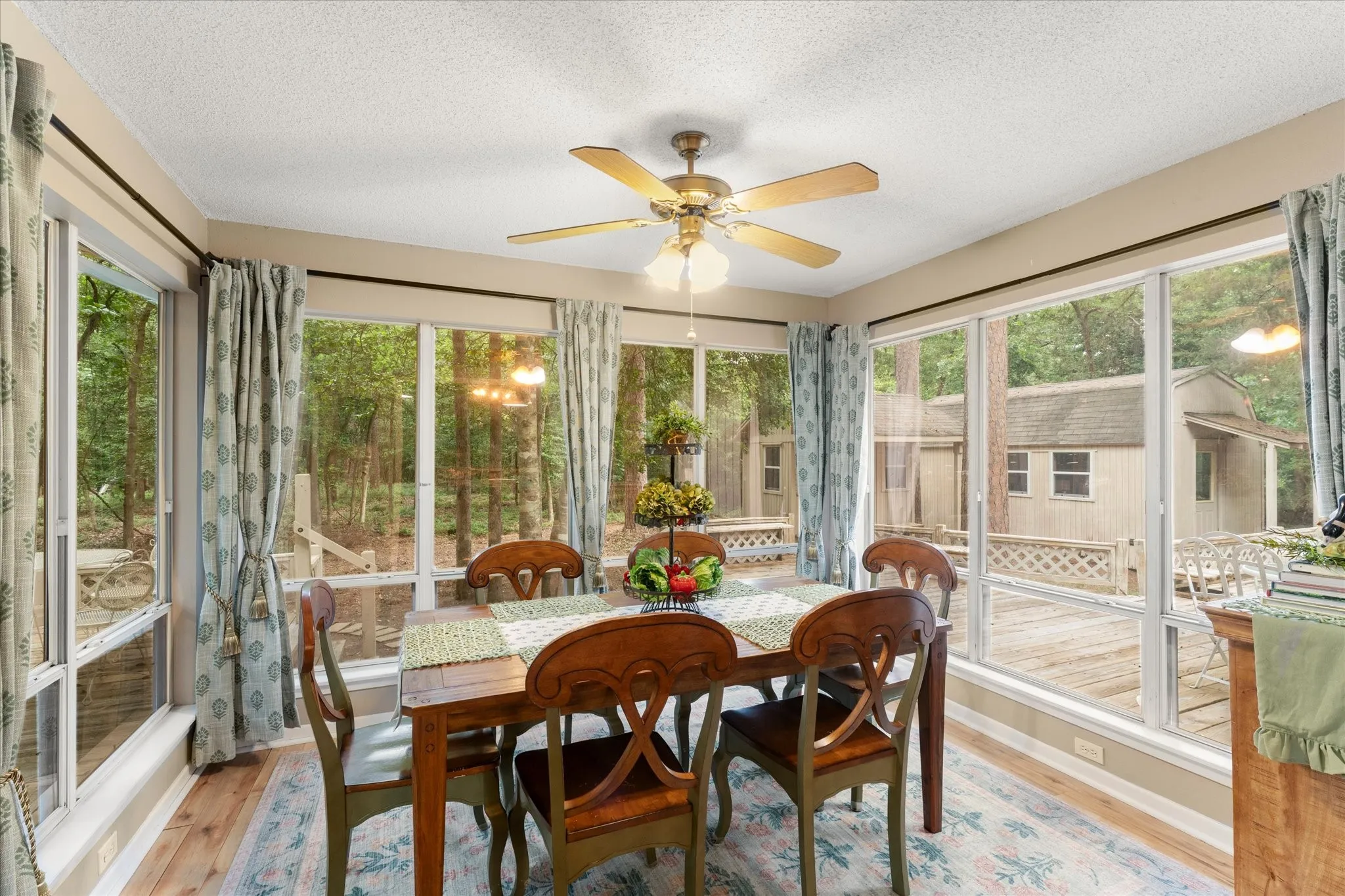 Dining area featuring wood-finish flooring, a ceiling fan with integrated lighting, and extensive window walls providing abundant natural light