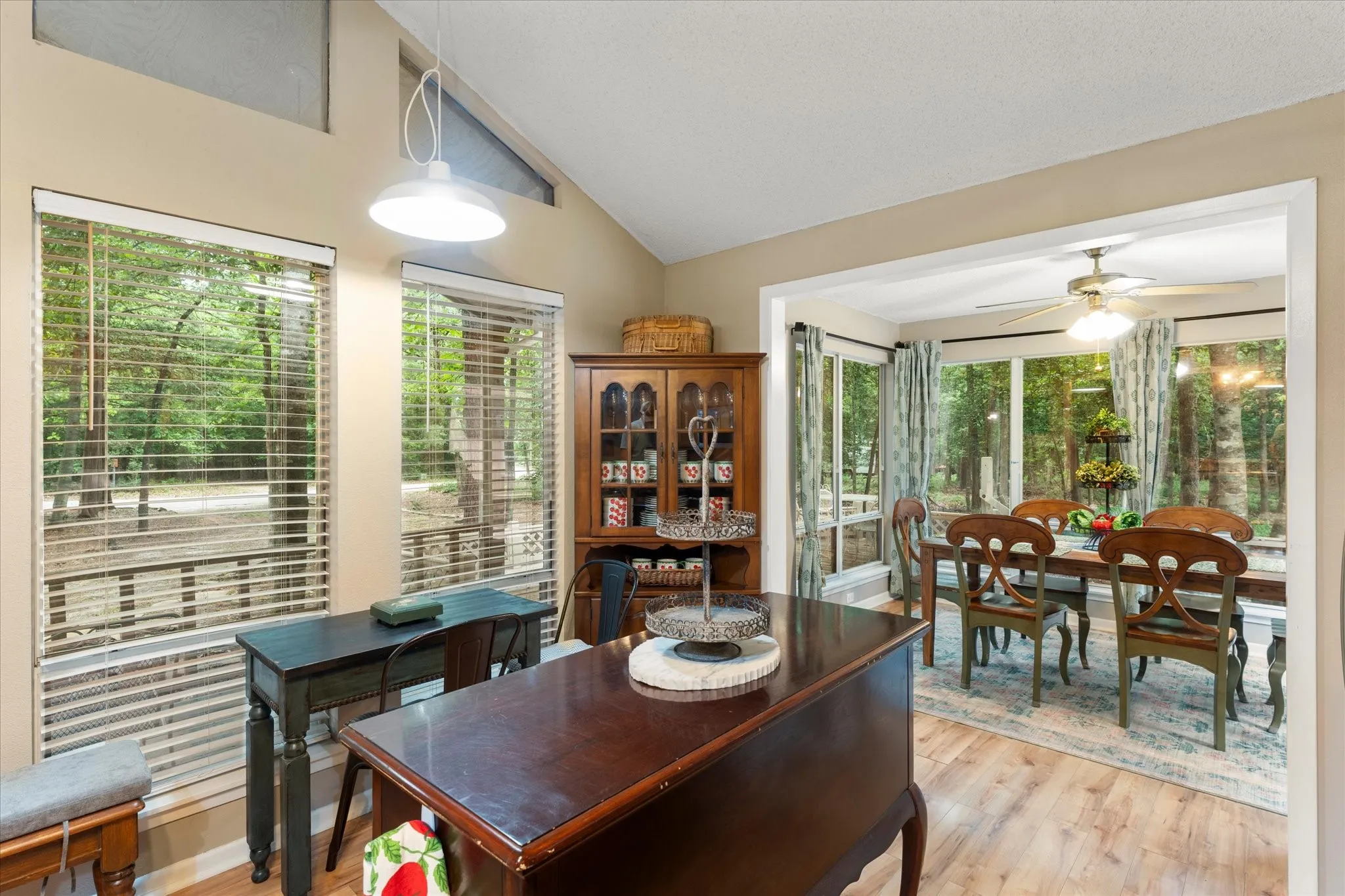 Vaulted ceiling with a white pendant light fixture and wood-finish flooring