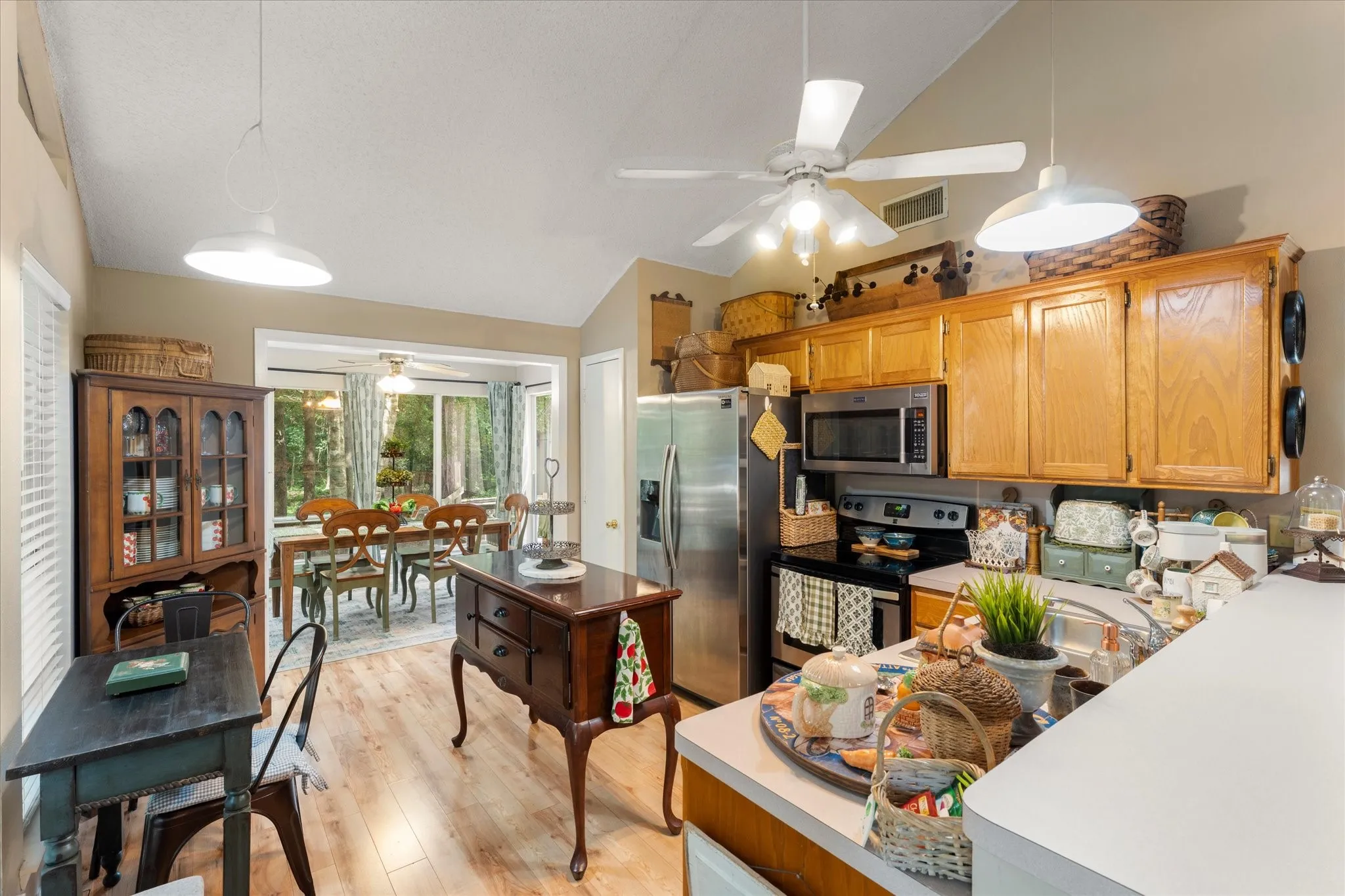 Kitchen featuring wood-finish flooring, oak cabinetry, stainless steel appliances, and a vaulted ceiling