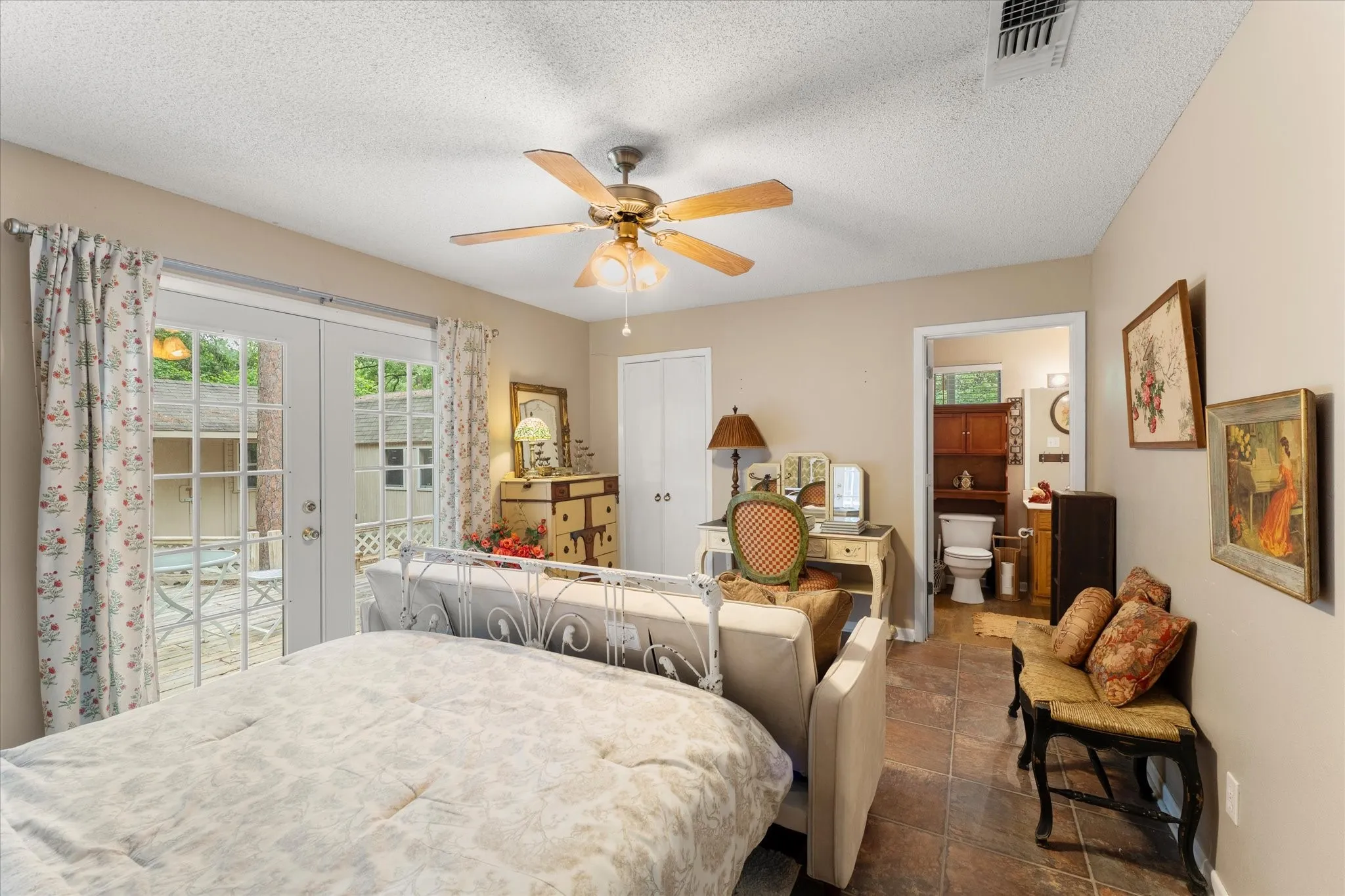 Room with dual glass-paneled French doors providing outdoor access, a ceiling fan, and tile flooring