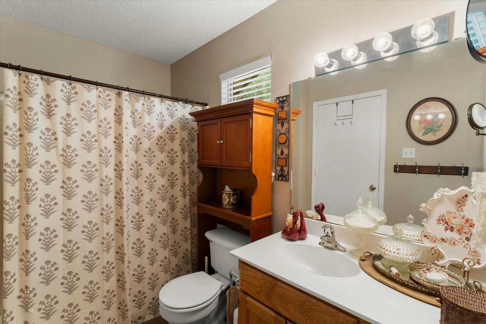 Bathroom featuring a vanity with a white countertop and integrated sink, wood-finish cabinetry, a large wall-mounted mirror, and a multi-bulb vanity light fixture