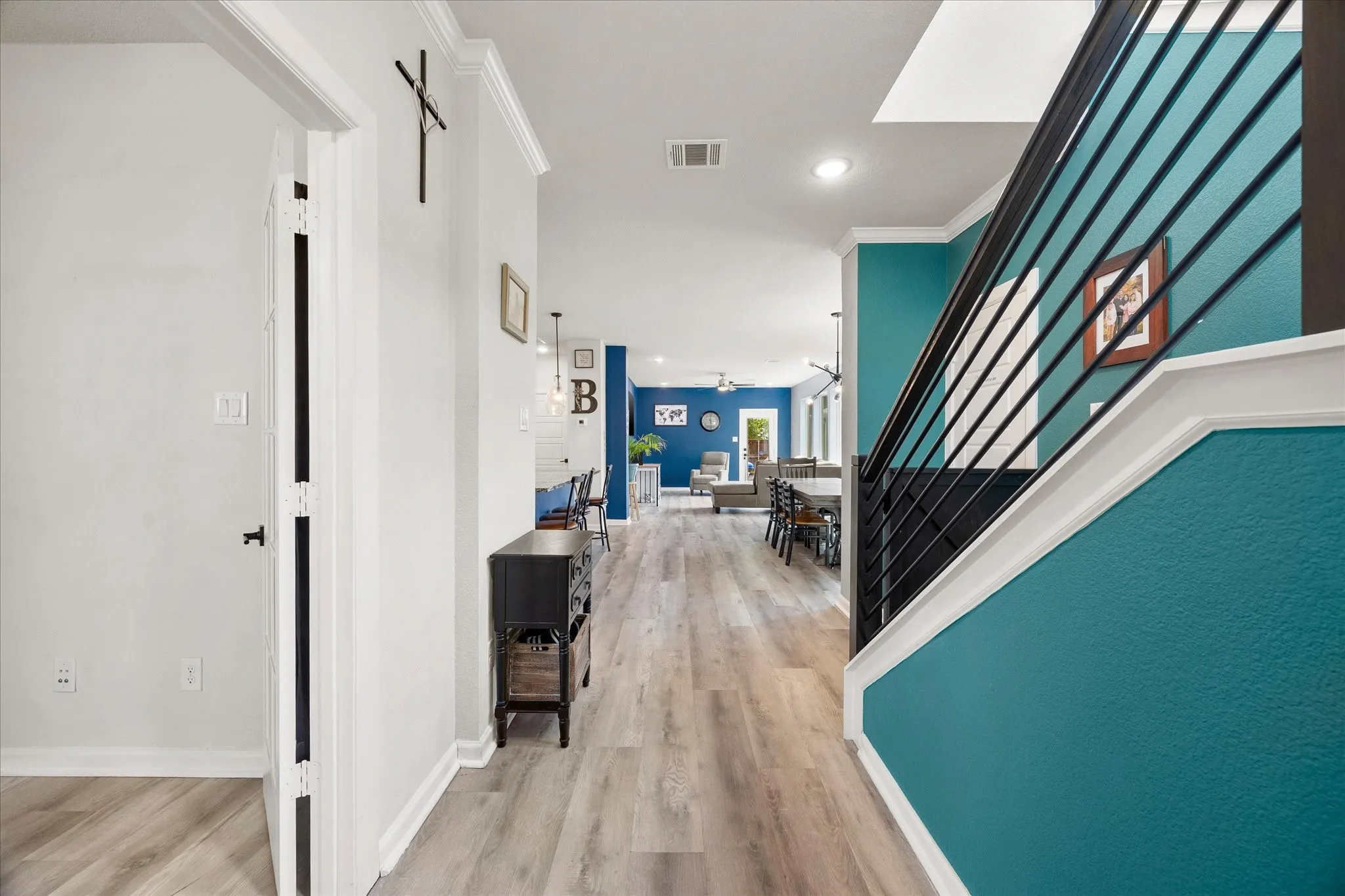 Light wood-finish flooring extends through the open concept layout, featuring a modern staircase with black metal balusters and white risers